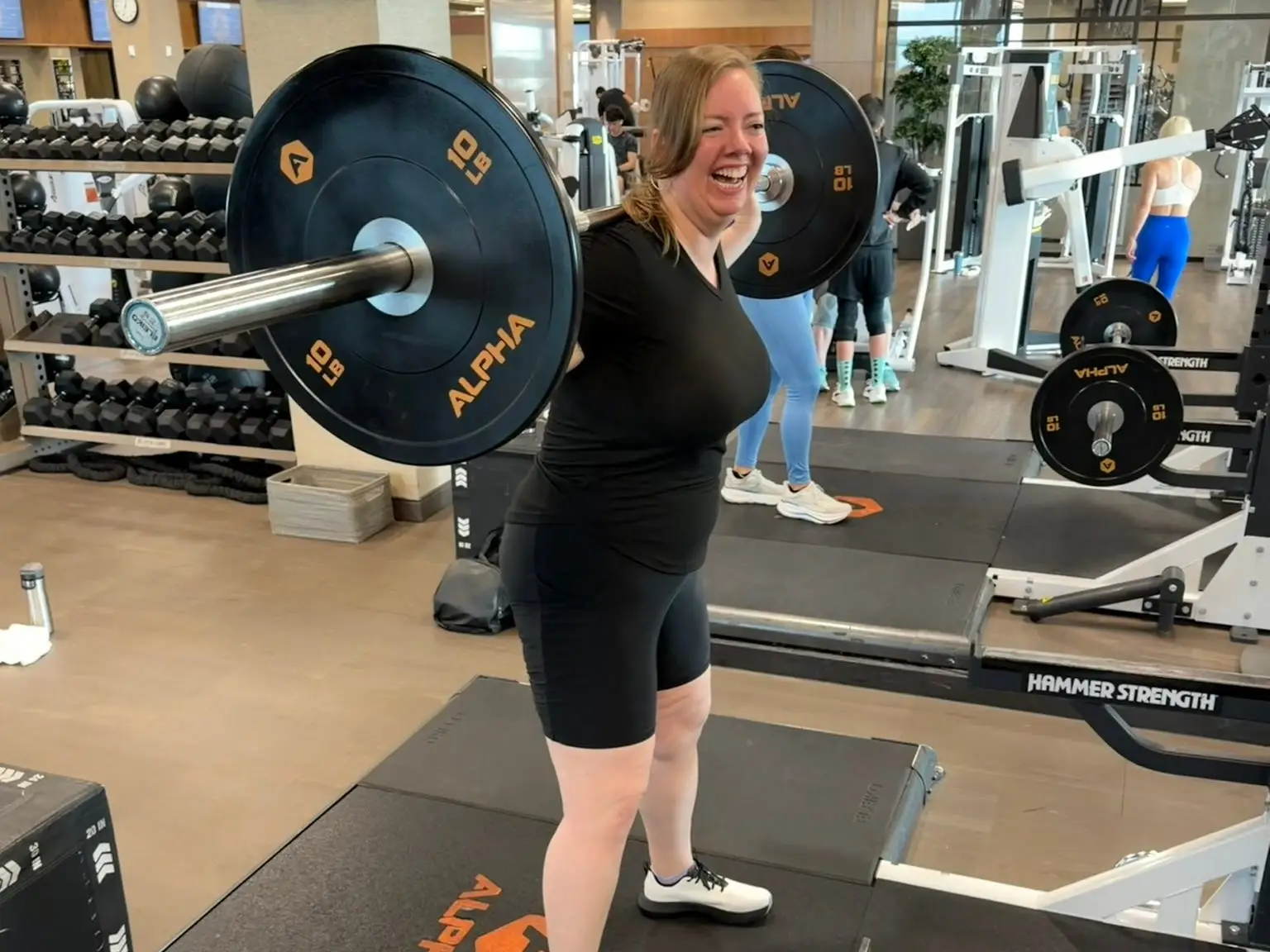 A woman is weightlifting at a gym.