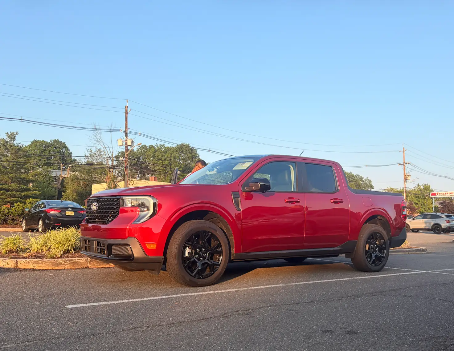 A red Ford Maverick is parked in a lot.