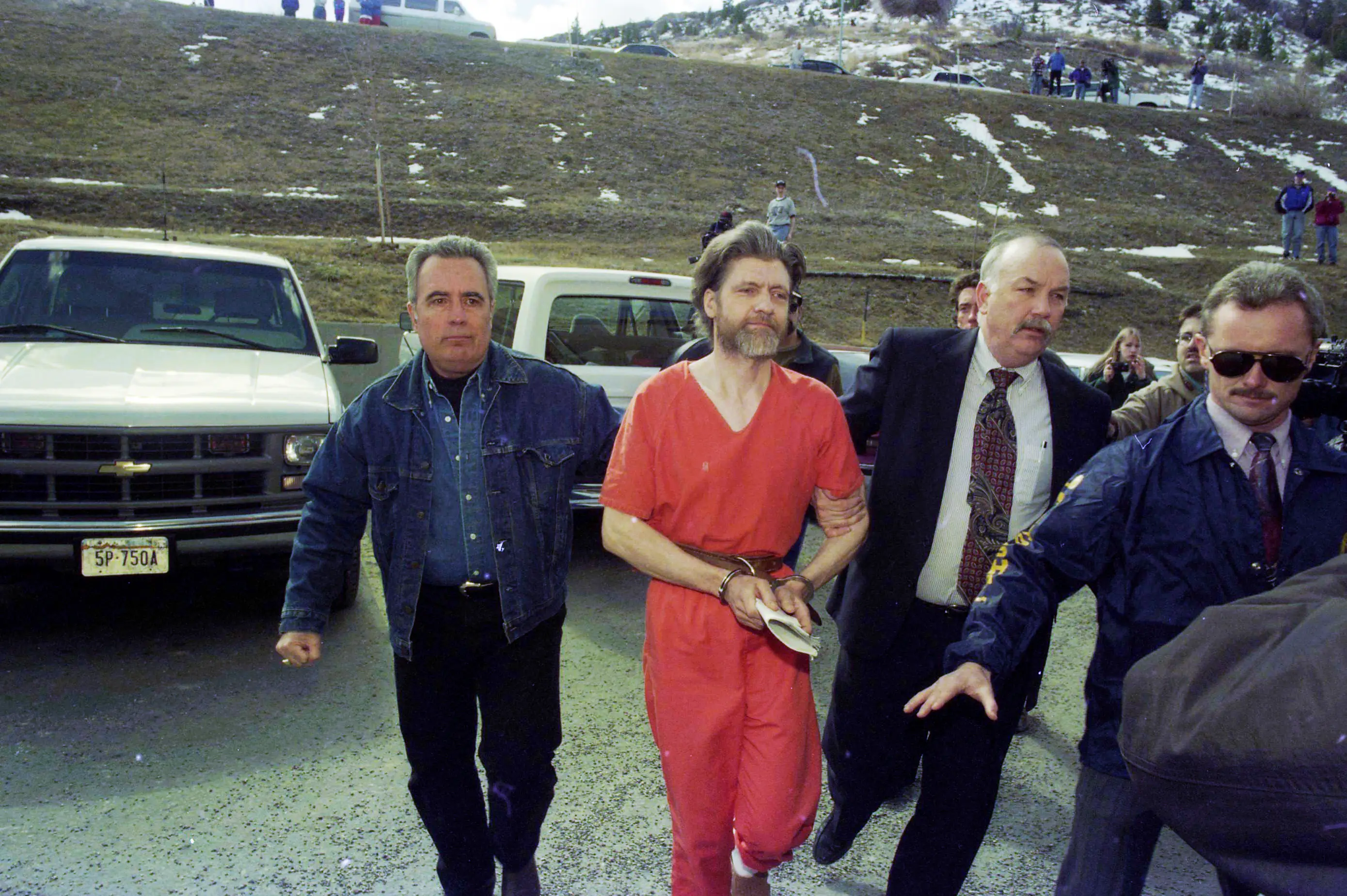 Theodore 'Ted' Kaczynski dressed in orange guided to his arraignment by federal marshals.
