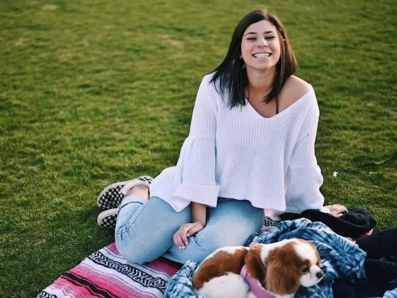 The author sitting on a blanket in some grass with her dog.