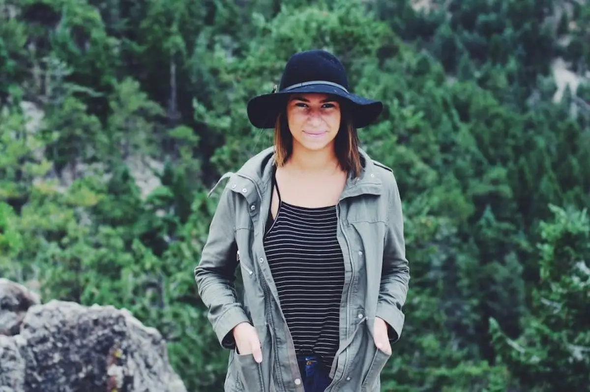 The author wearing a green jacket and black hat with a backdrop of trees