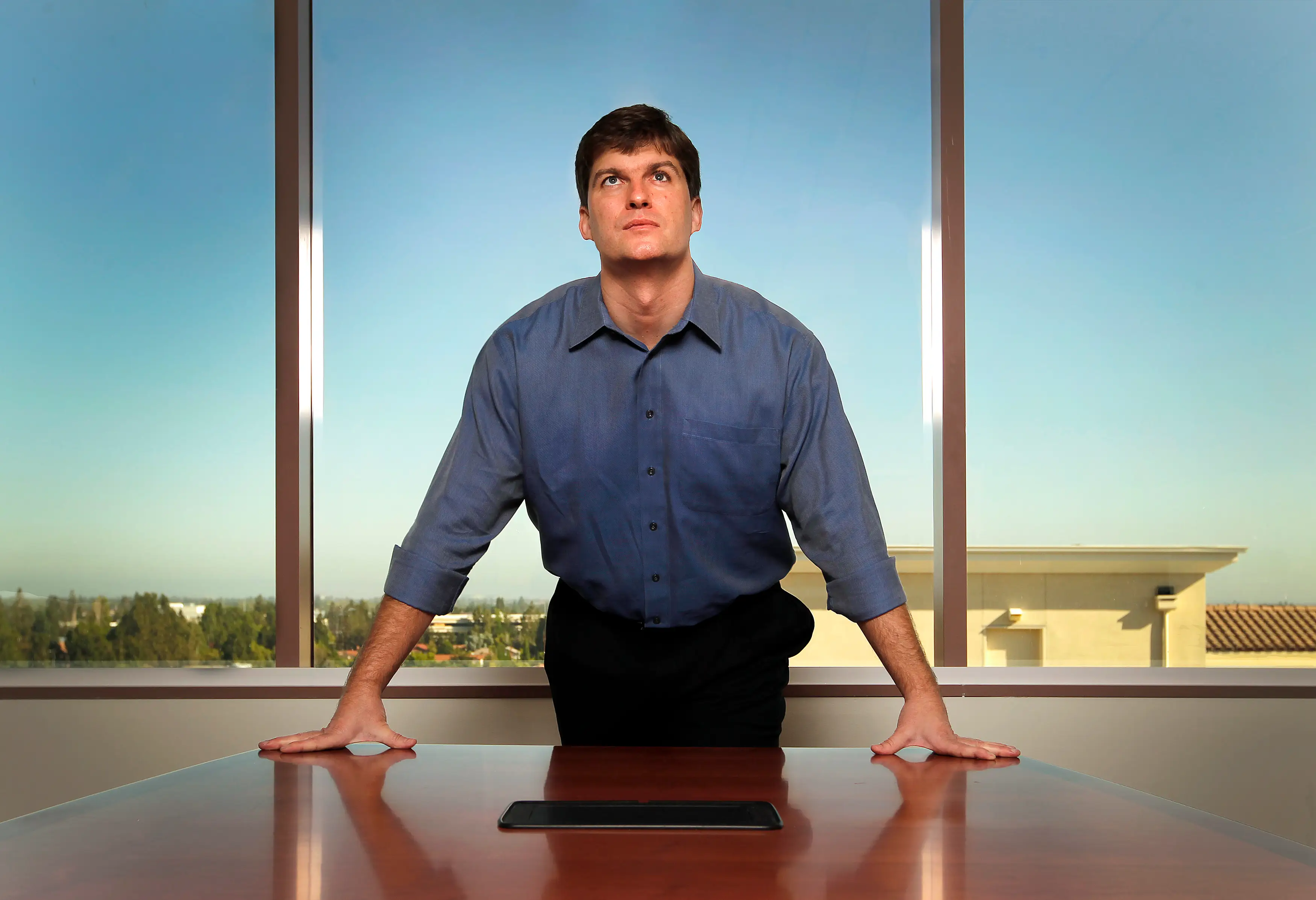 Michael Burry posing for a portrait over a desk