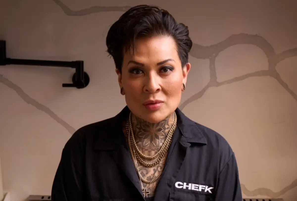 Chef K faces the camera wearing a black shirt labeled