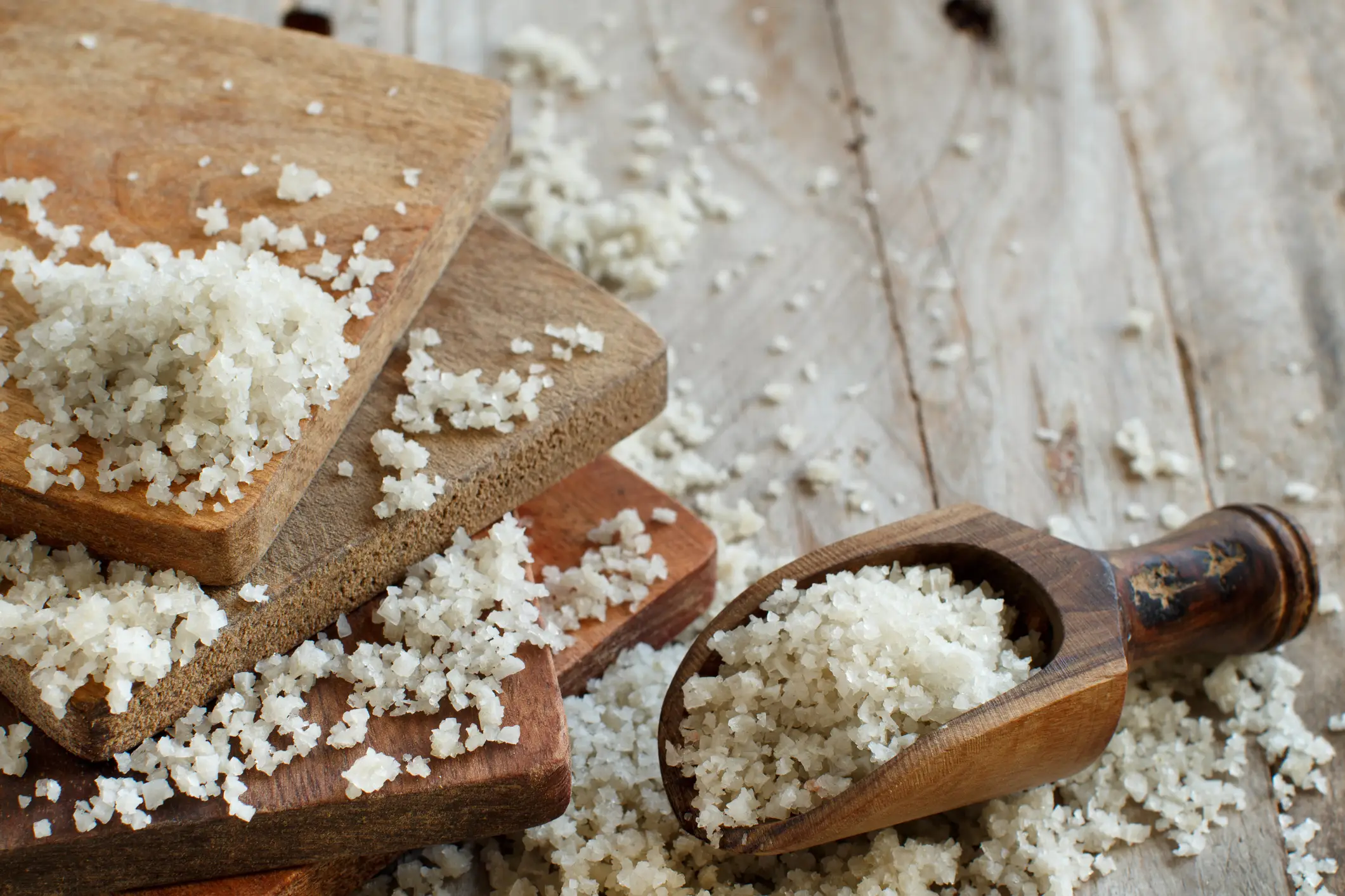 Celtic sea salt spead out across chopping boards and a spoon.