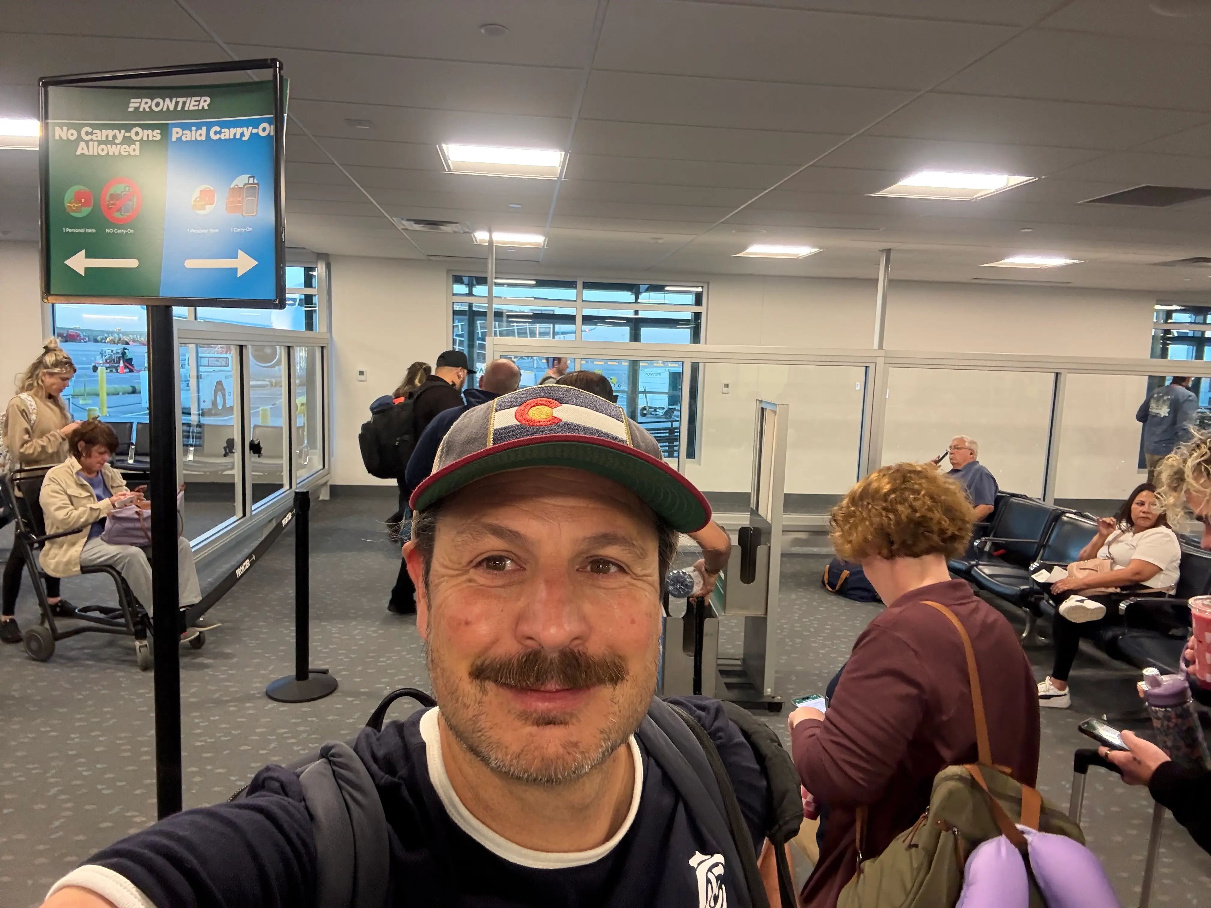 Man smiling near Frontier boarding gate in airport