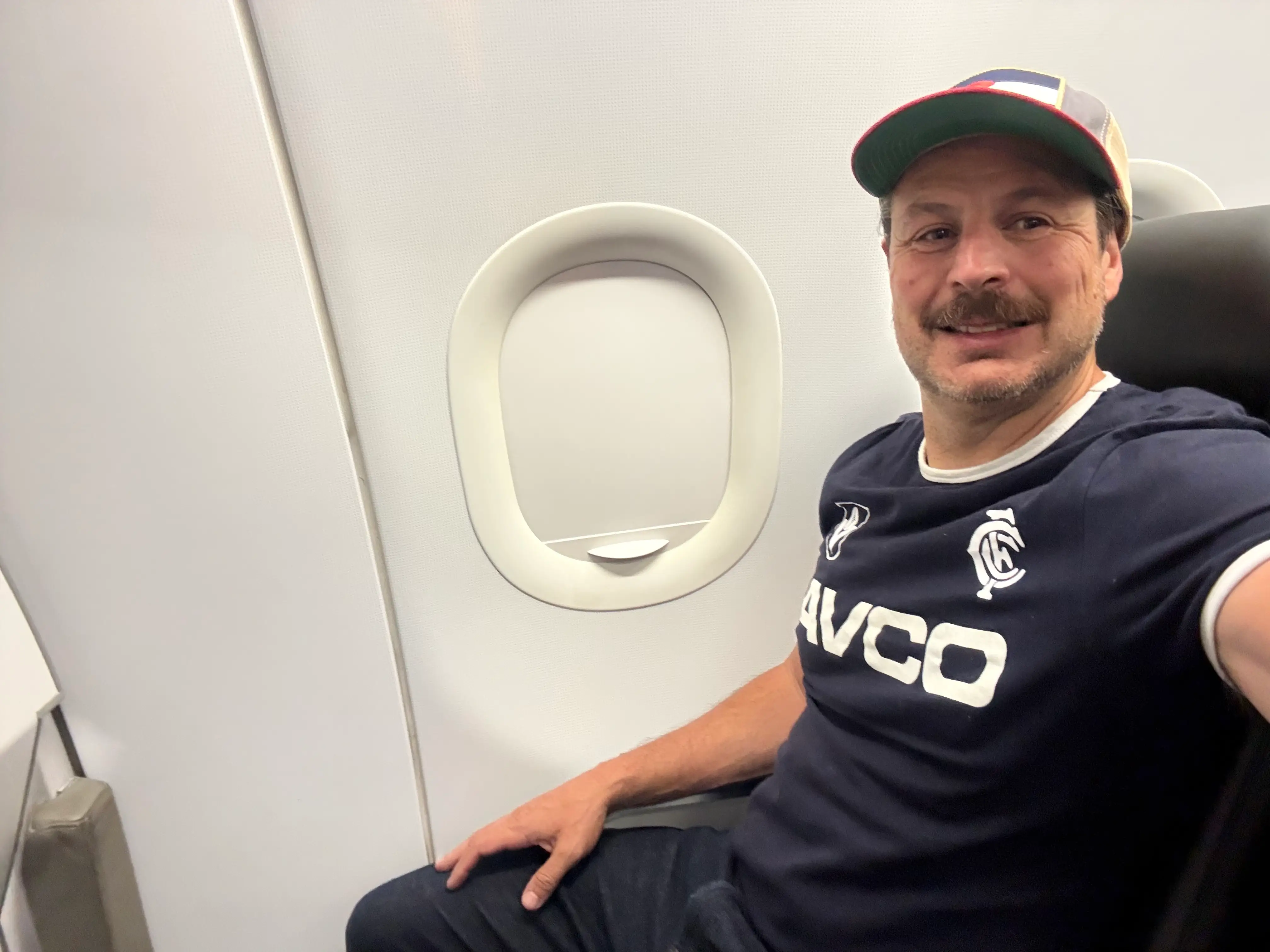 Man smiling in window seat in Frontier UpFront row