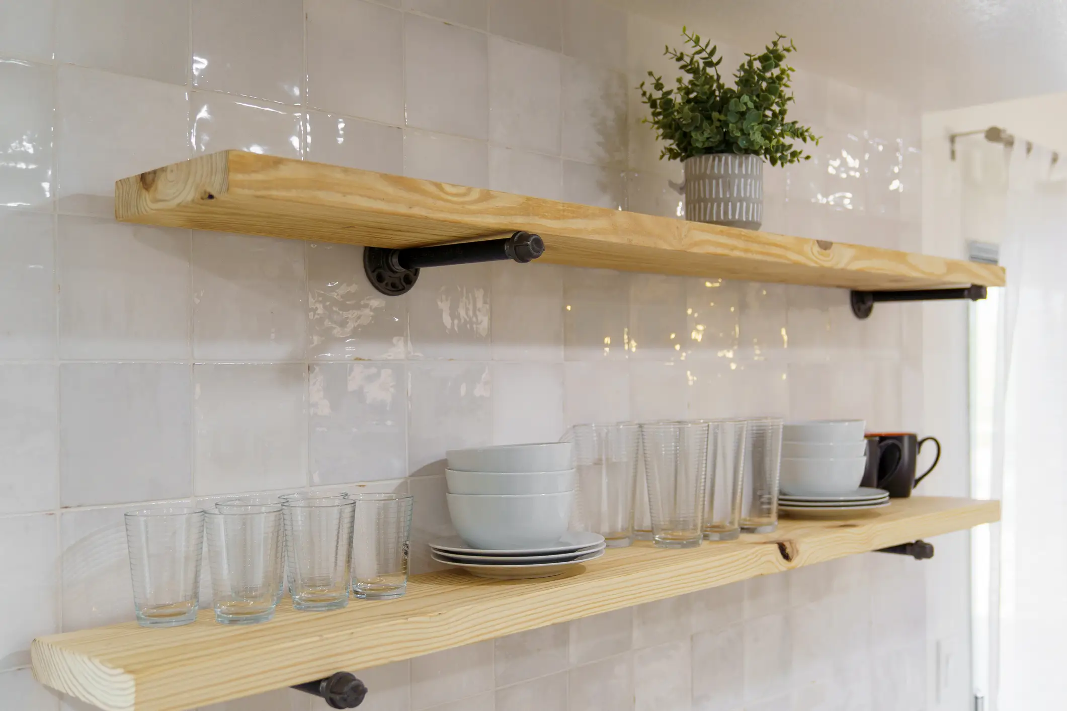 Wooden Shelves with Industrial Pipe Brackets  in kitchen with glassware, dishes on top