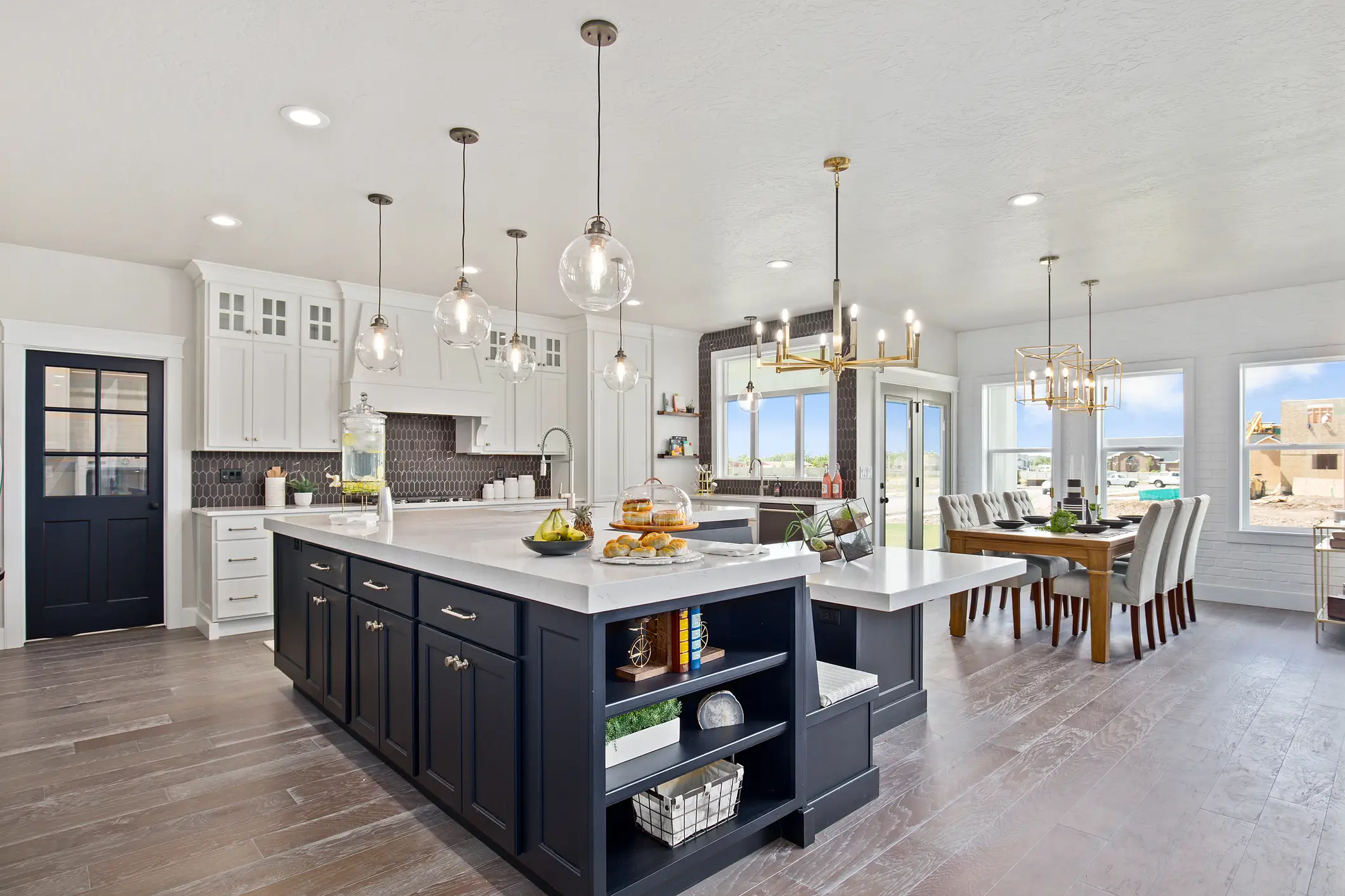 Open concept kitchen and dining area with navy cabinets on island and white cabinets against wall