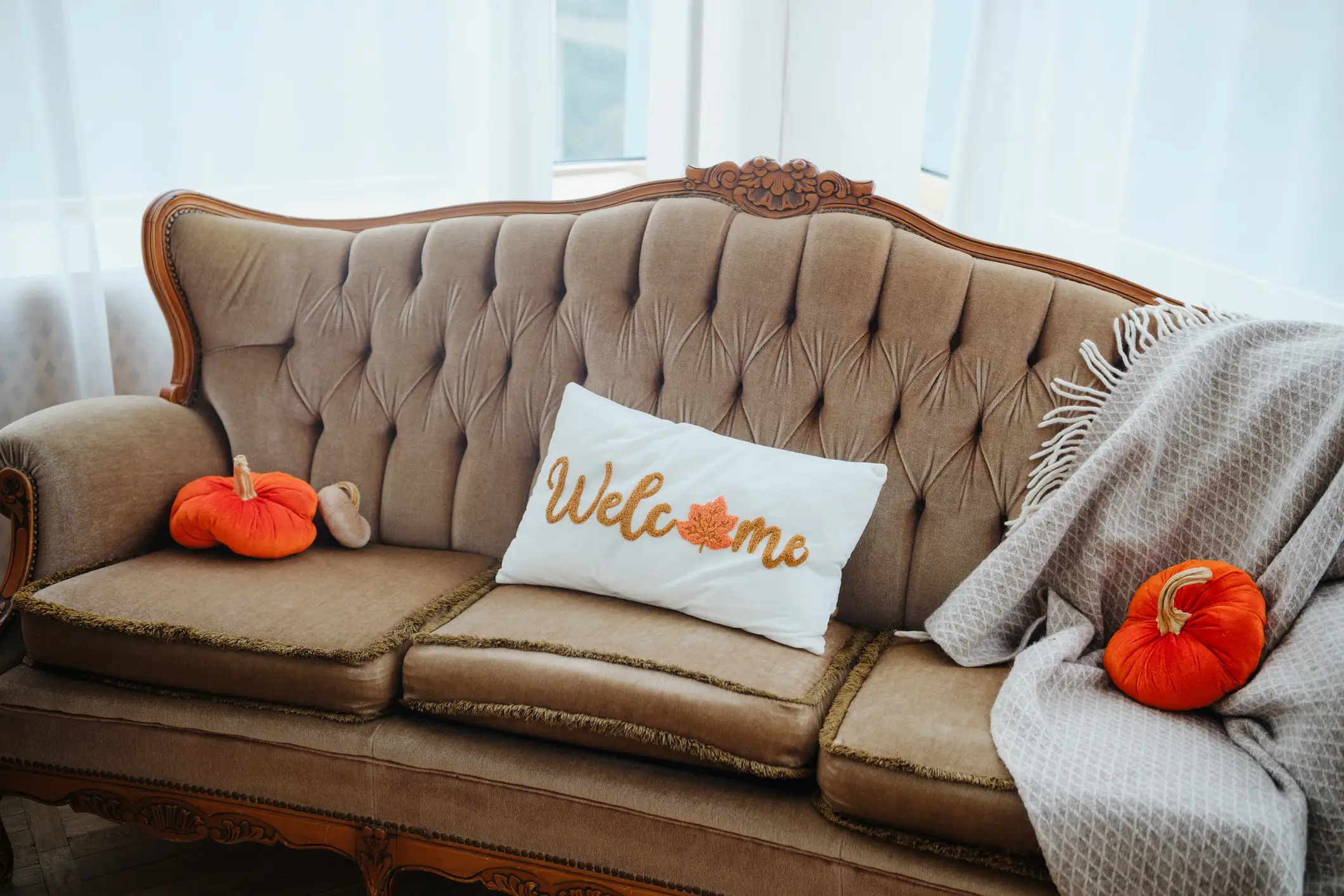 Tufted  sofa with pumpkin pillow, throw blanket on it