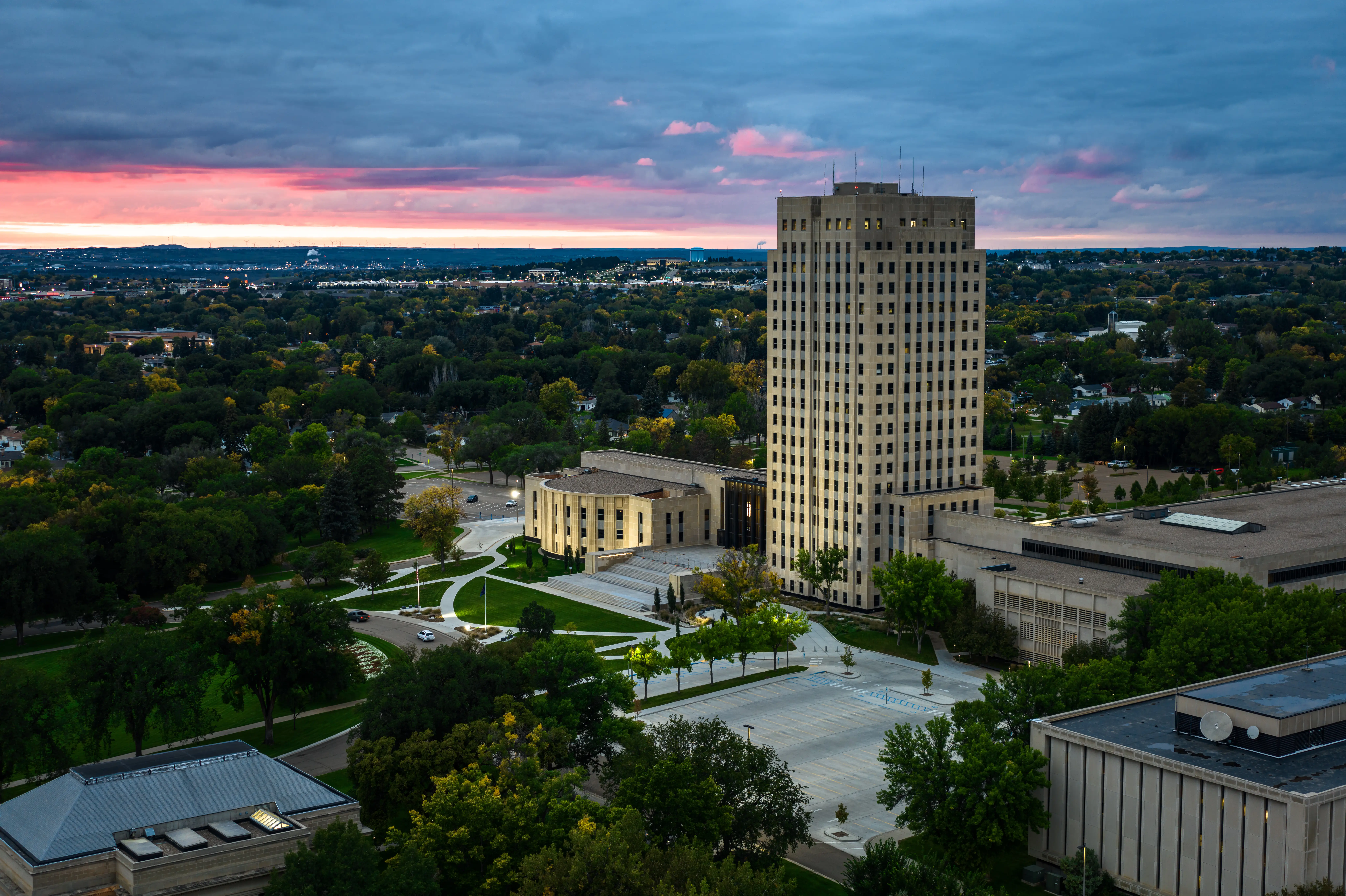 Aerial view of the North Dakota State Capitol in Bismarck, North Dakota, on a dramatic overcast sunset with a red-tinted sky in the fall.