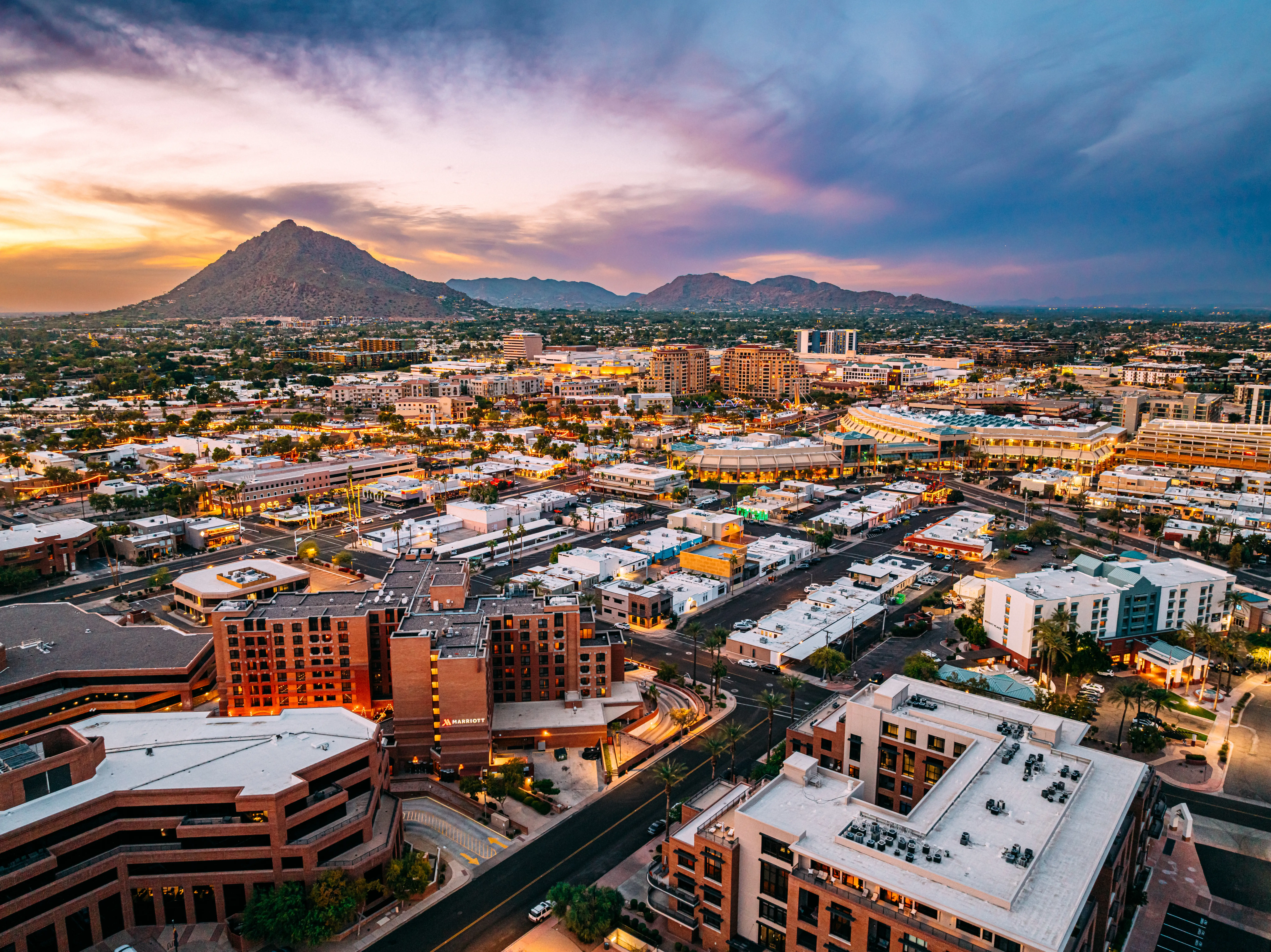 Aerial cityscape of Scottsdale, Arizona, under a colorful sunset sky.