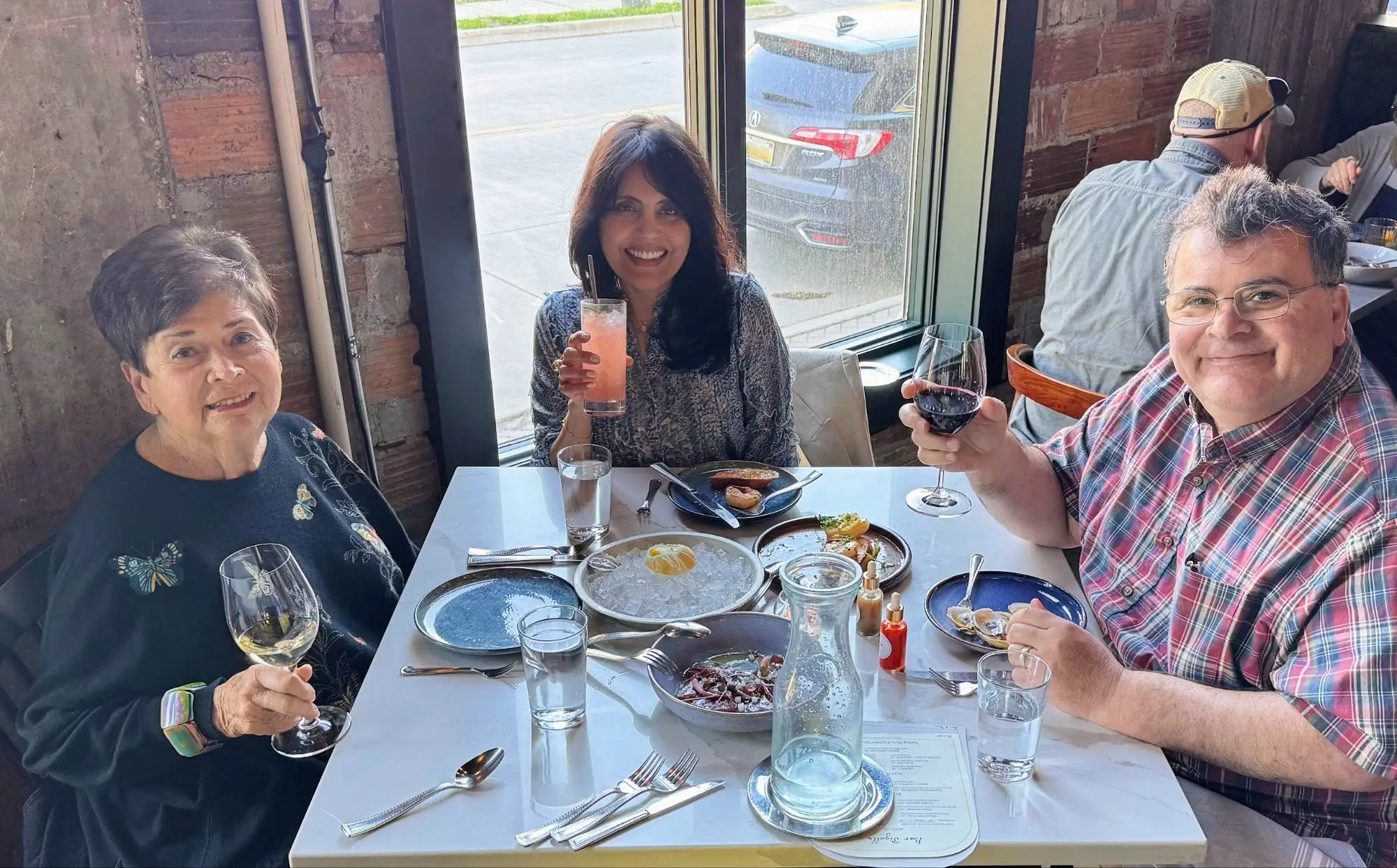 Man and. two women holding up drinks at a dinner