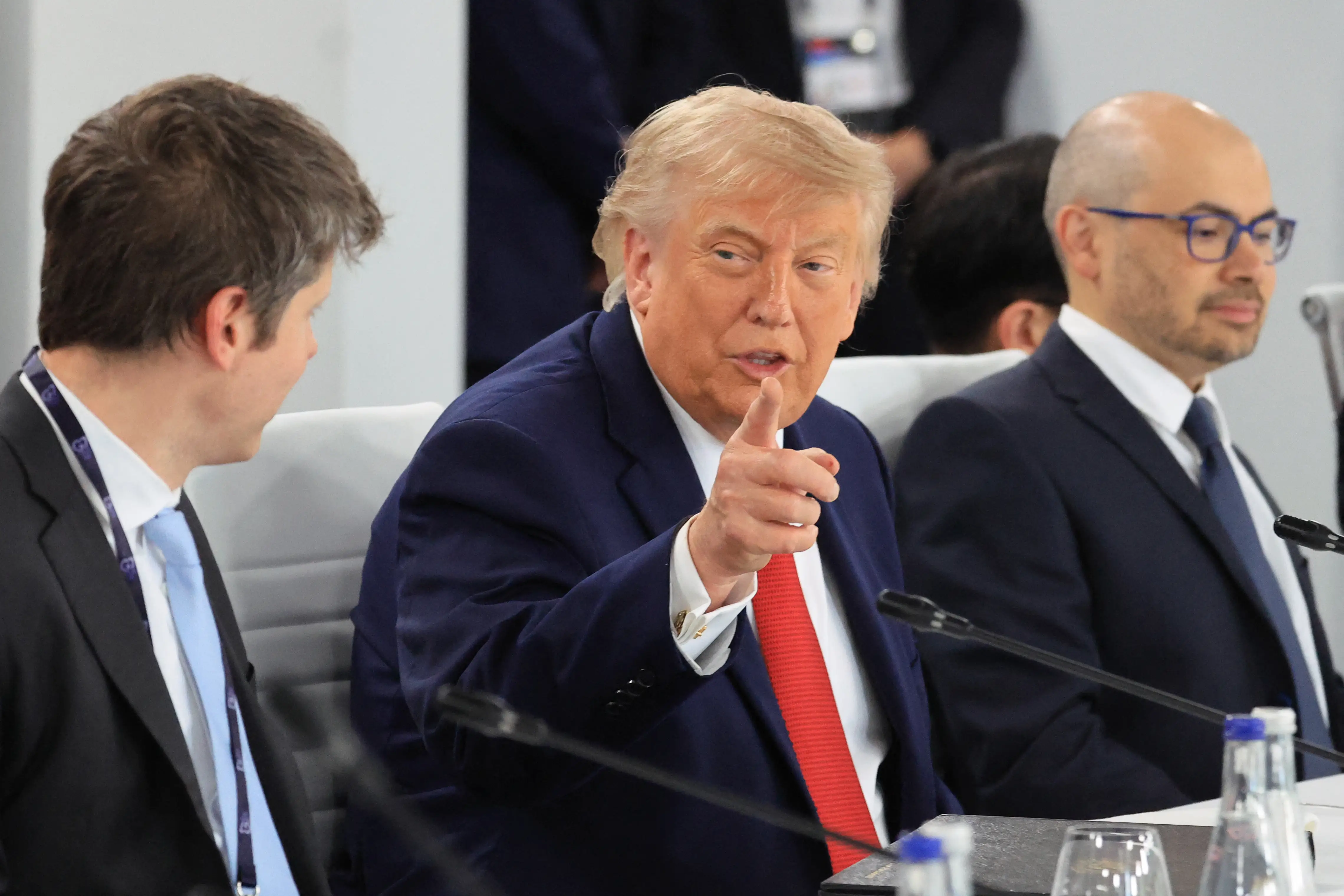 Donald Trump gestures while sitting with OpenAI CEO Sam Altman and Google DeepMind CEO Demis Hassabis.