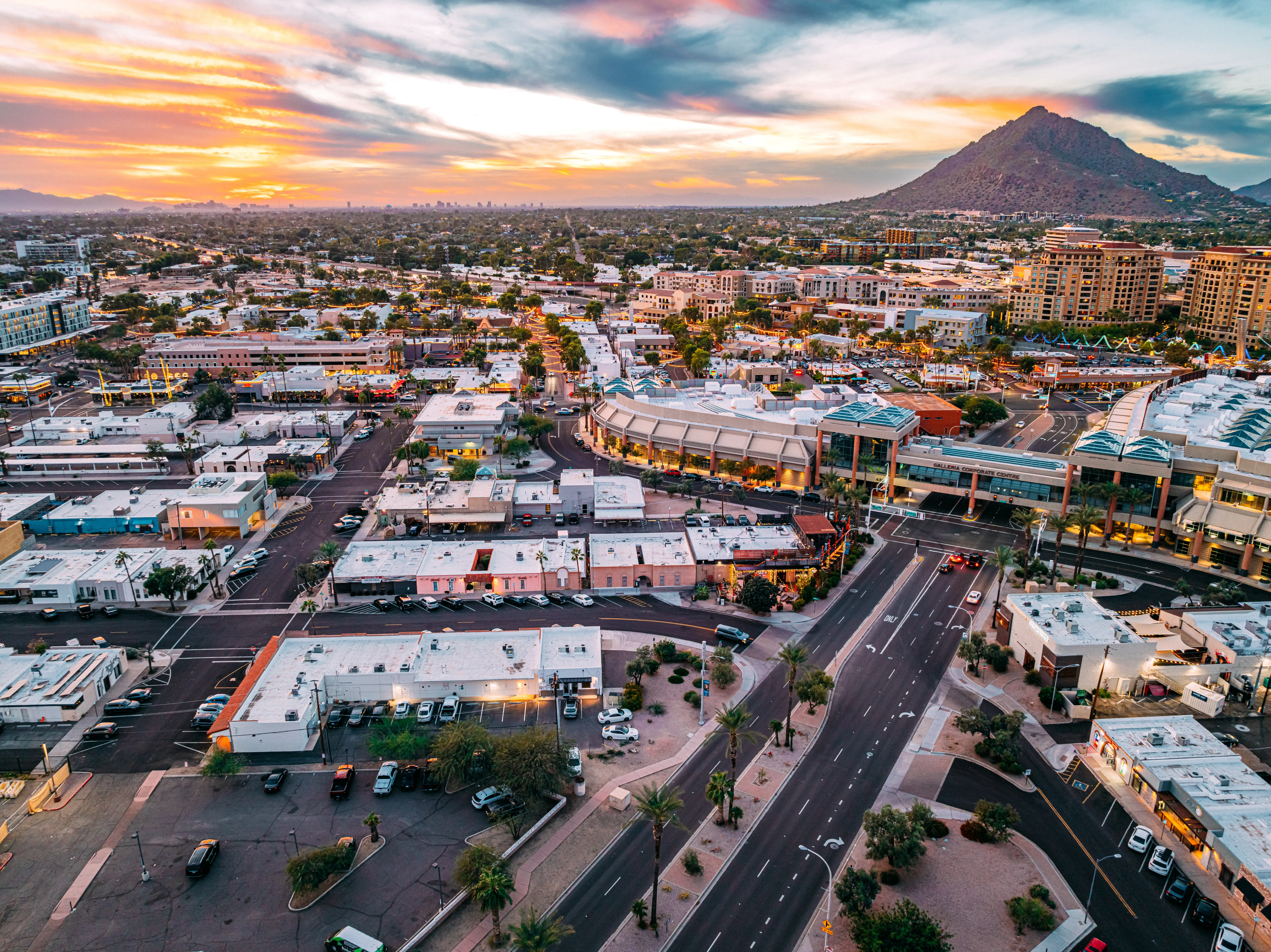 Aerial view of urban streets and shopping buildings at sunset.