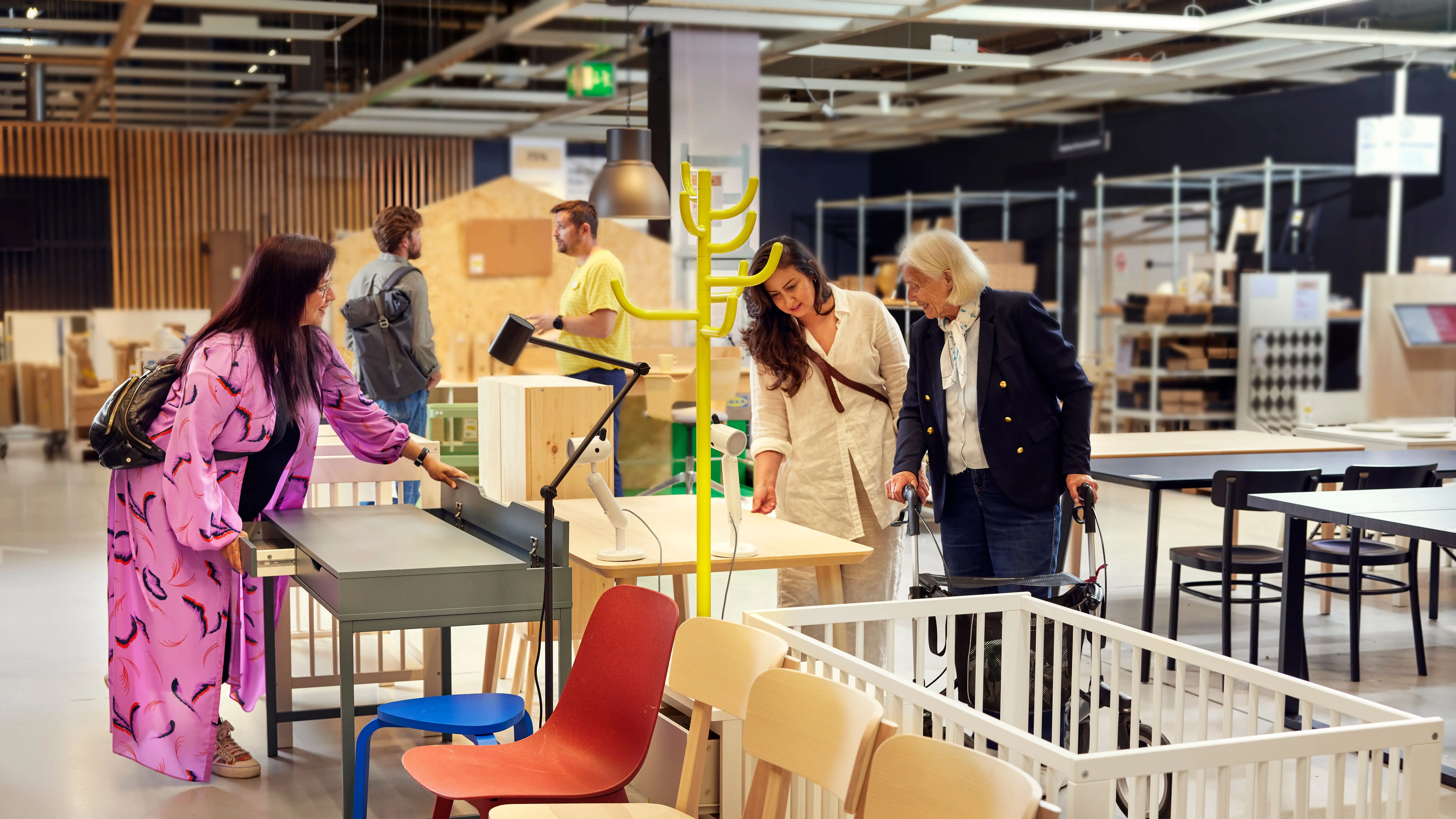 Customers look at furniture in the As-Is section of an Ikea store, including desks, table lamps, and chairs.