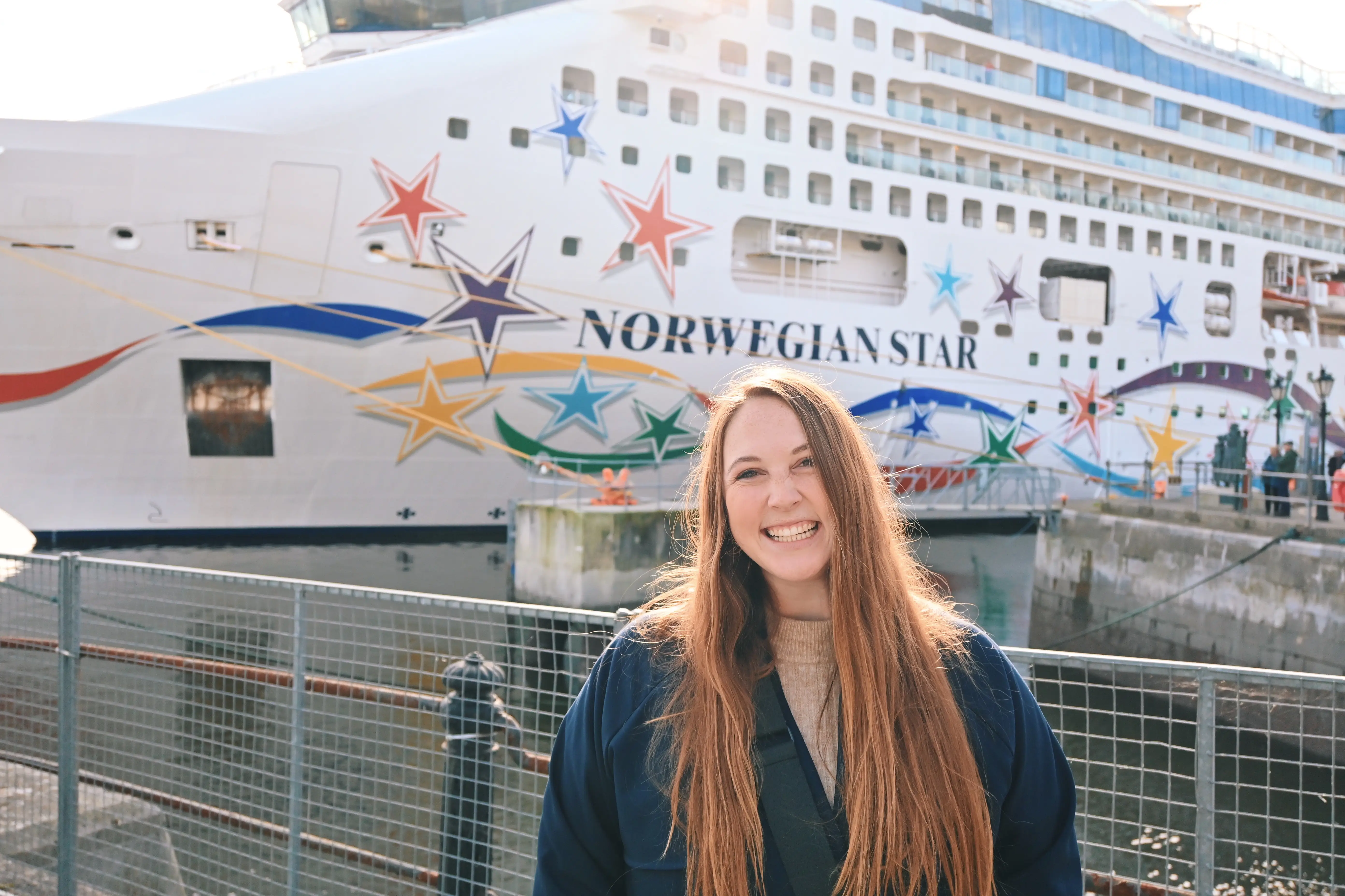 Woman smiling in front of Norwegian Star cruise ship