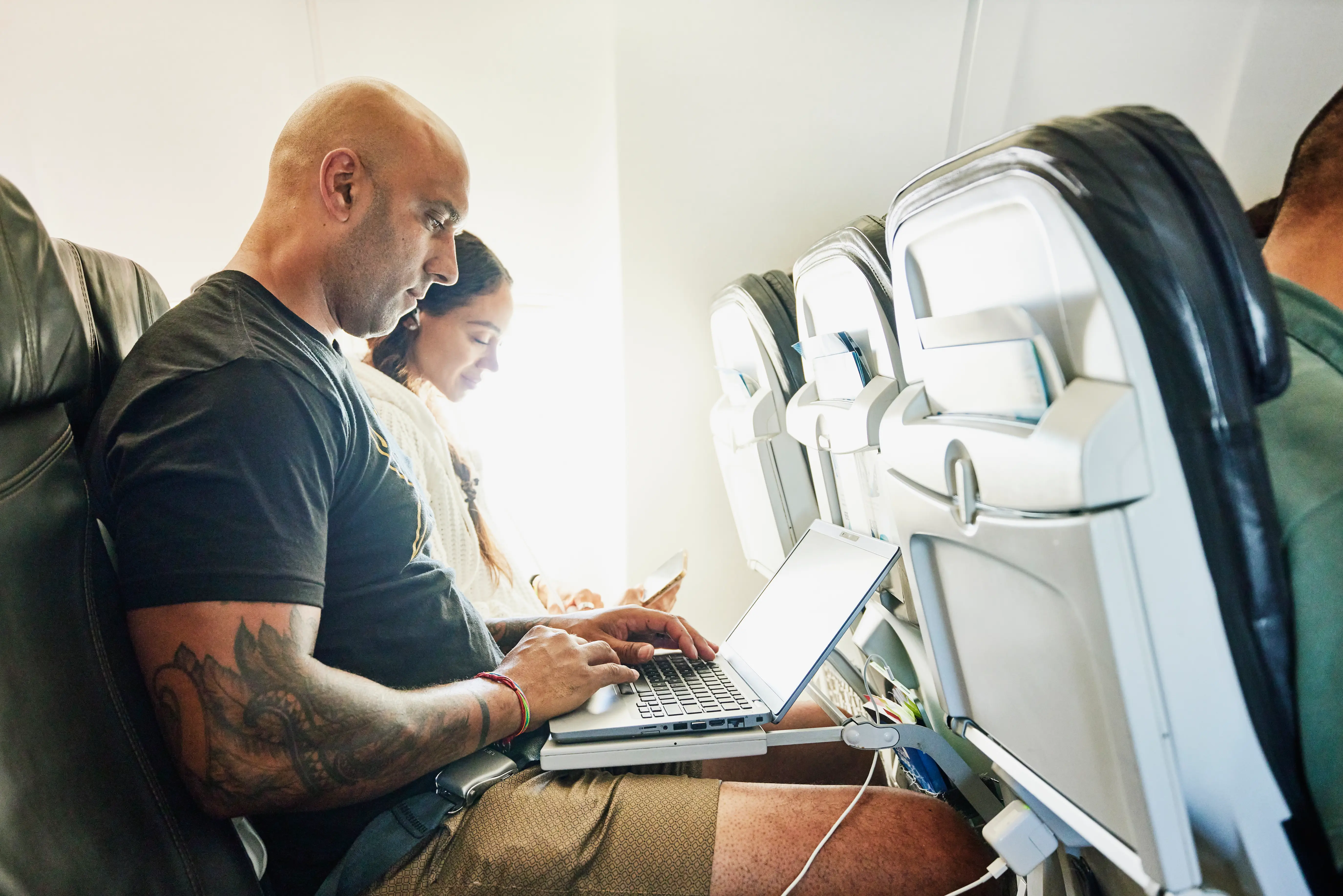 Man working on a laptop on a plane.