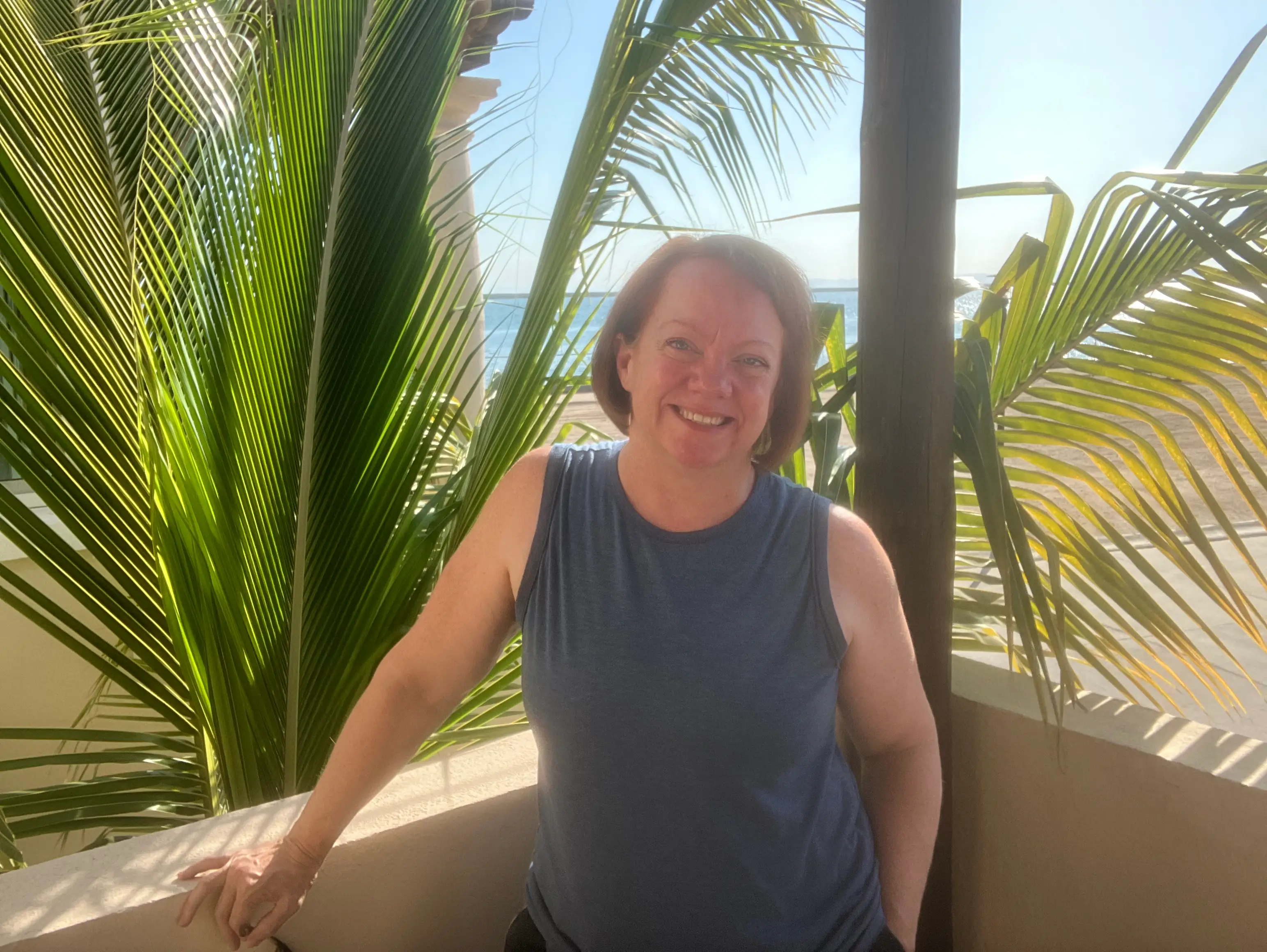 Woman smiling in front of palm leaves