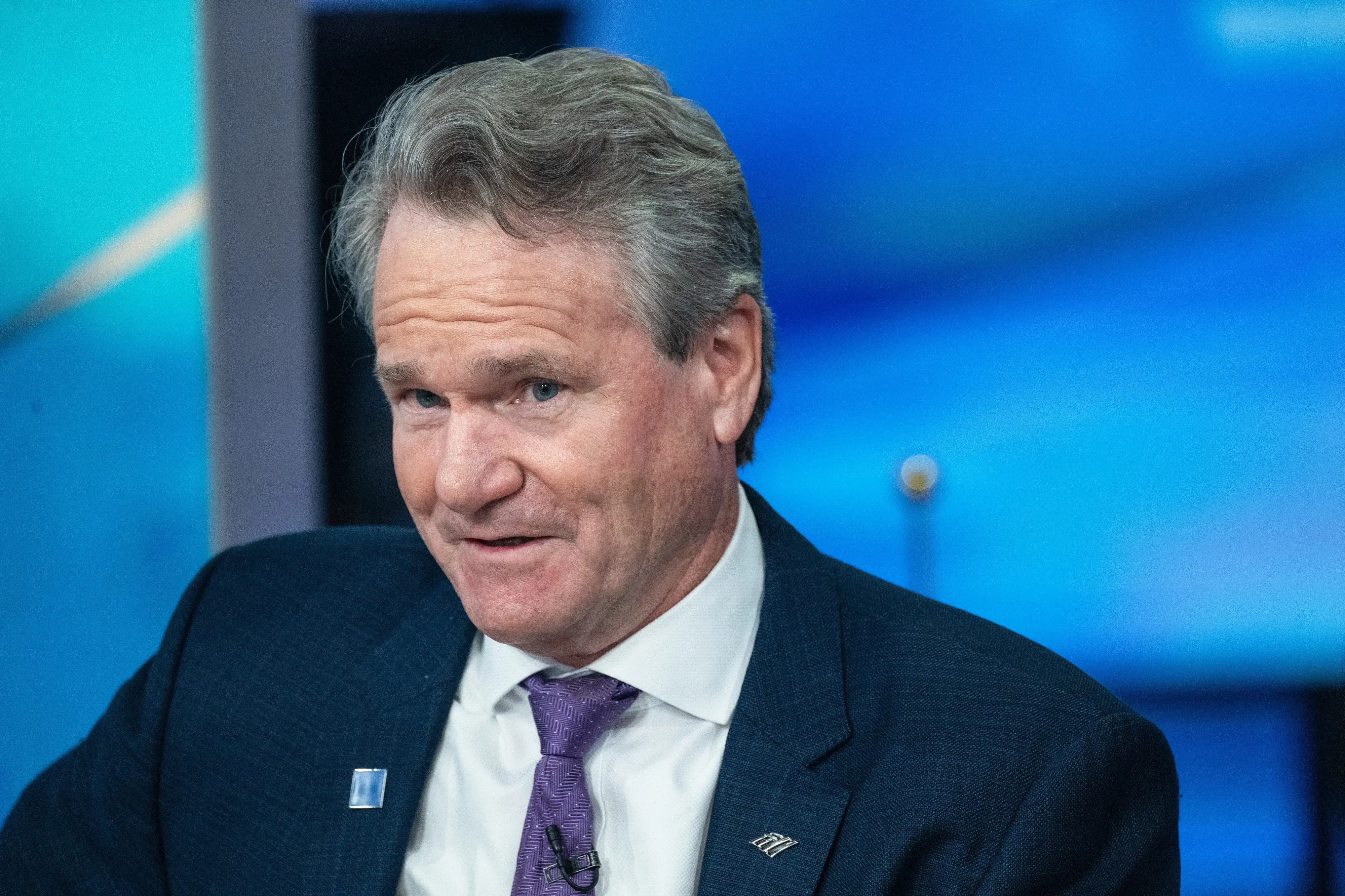 Brian Moynihan sits in a television studio wearing a dark suit and purple tie.