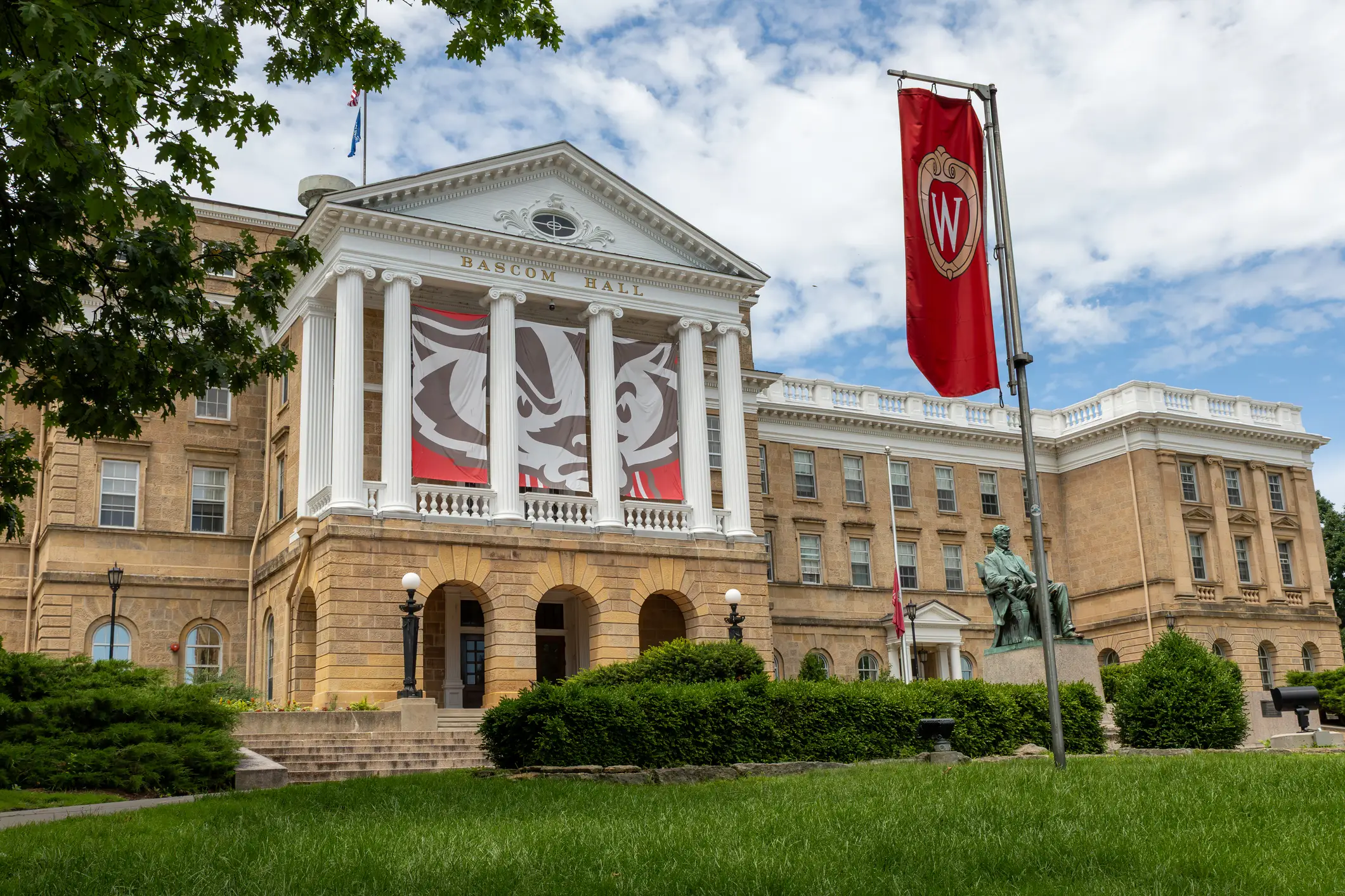 Bascom Hall located on the University of Wisconsin, Madison campus in Madison Wisconsin framed by tree and banner.
