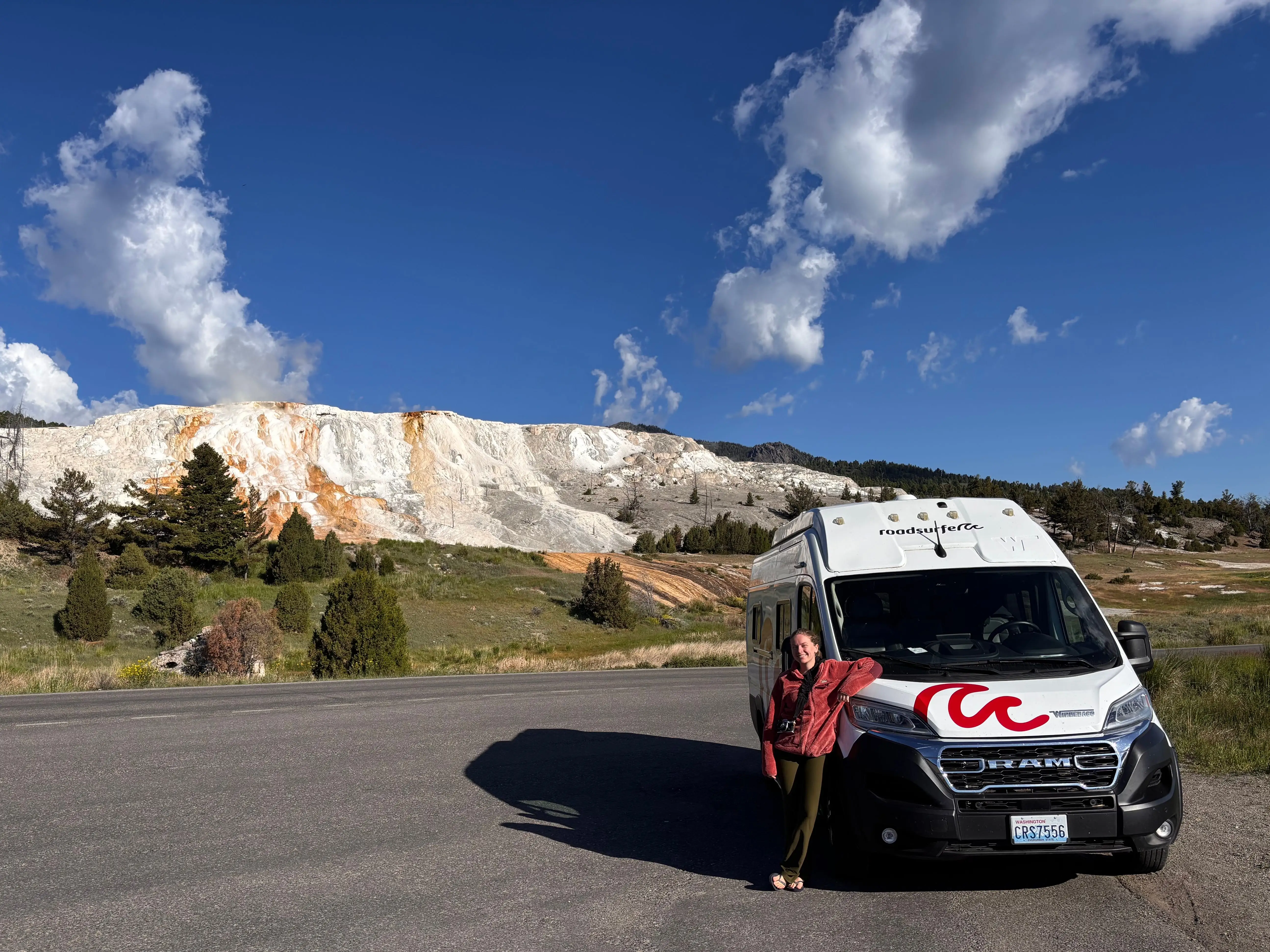 The writer is posing for a photo next to a van in Yellowstone National Park.