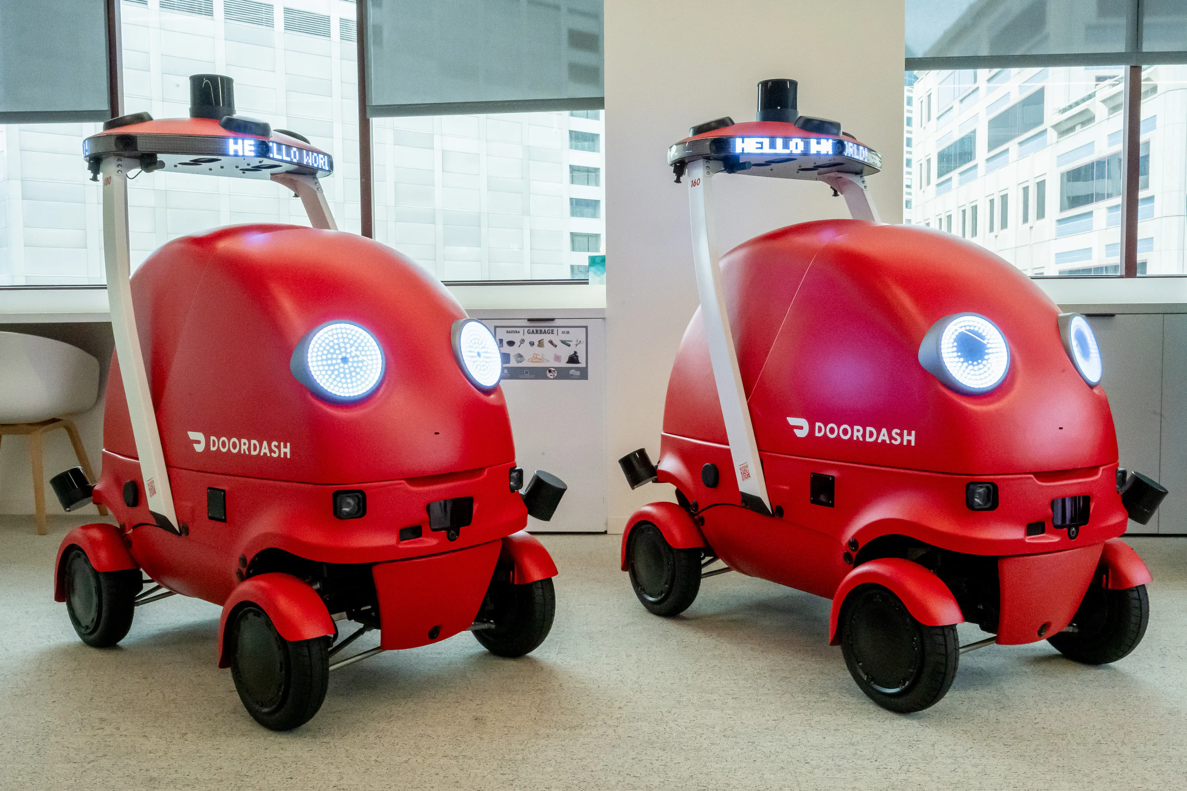 Two DoorDash Dot delivery robots sit in a conference room at DoorDash headquarters in San Francisco