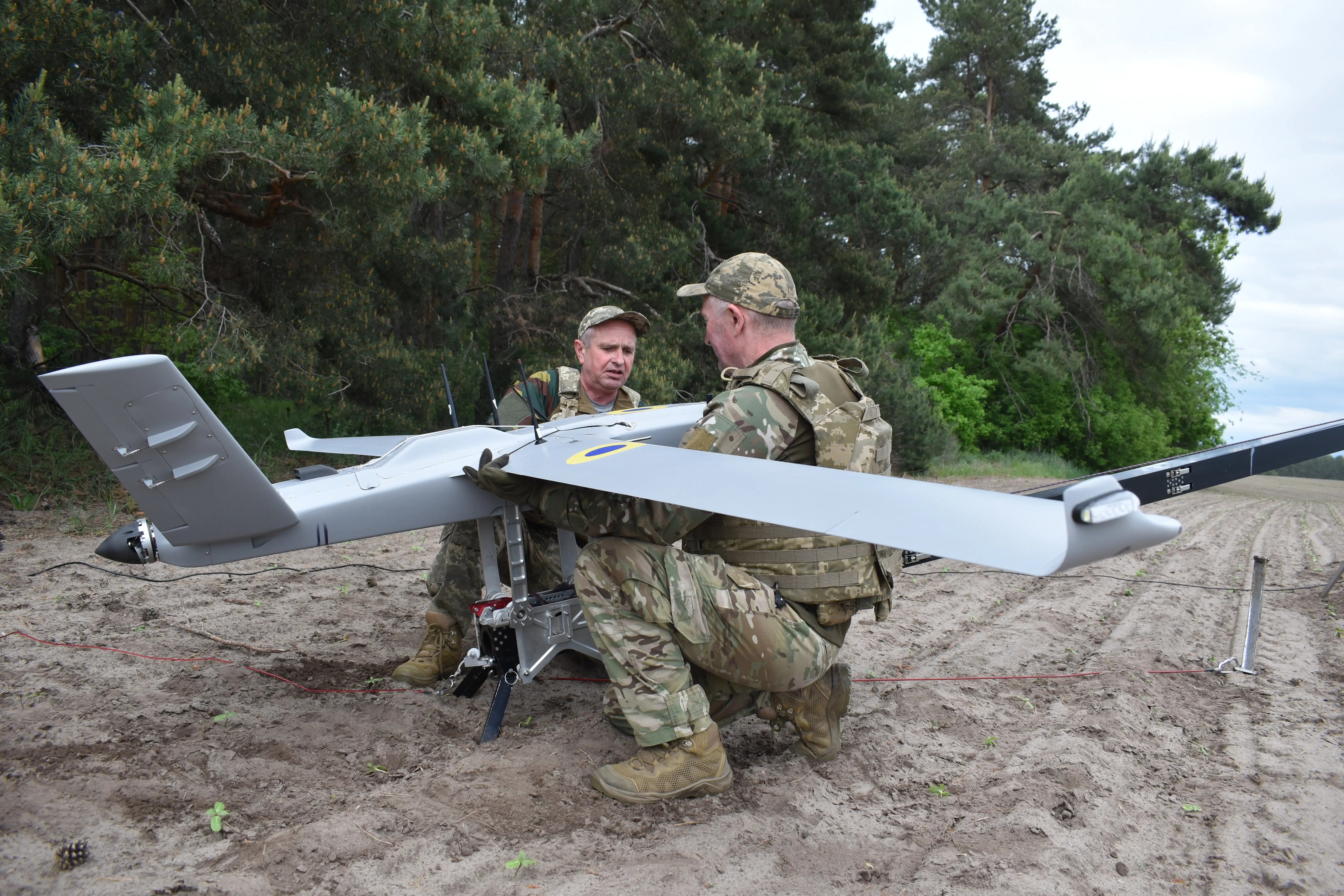 Two Ukrainian soldiers attach a Western surveillance drone to a catapult launch system.