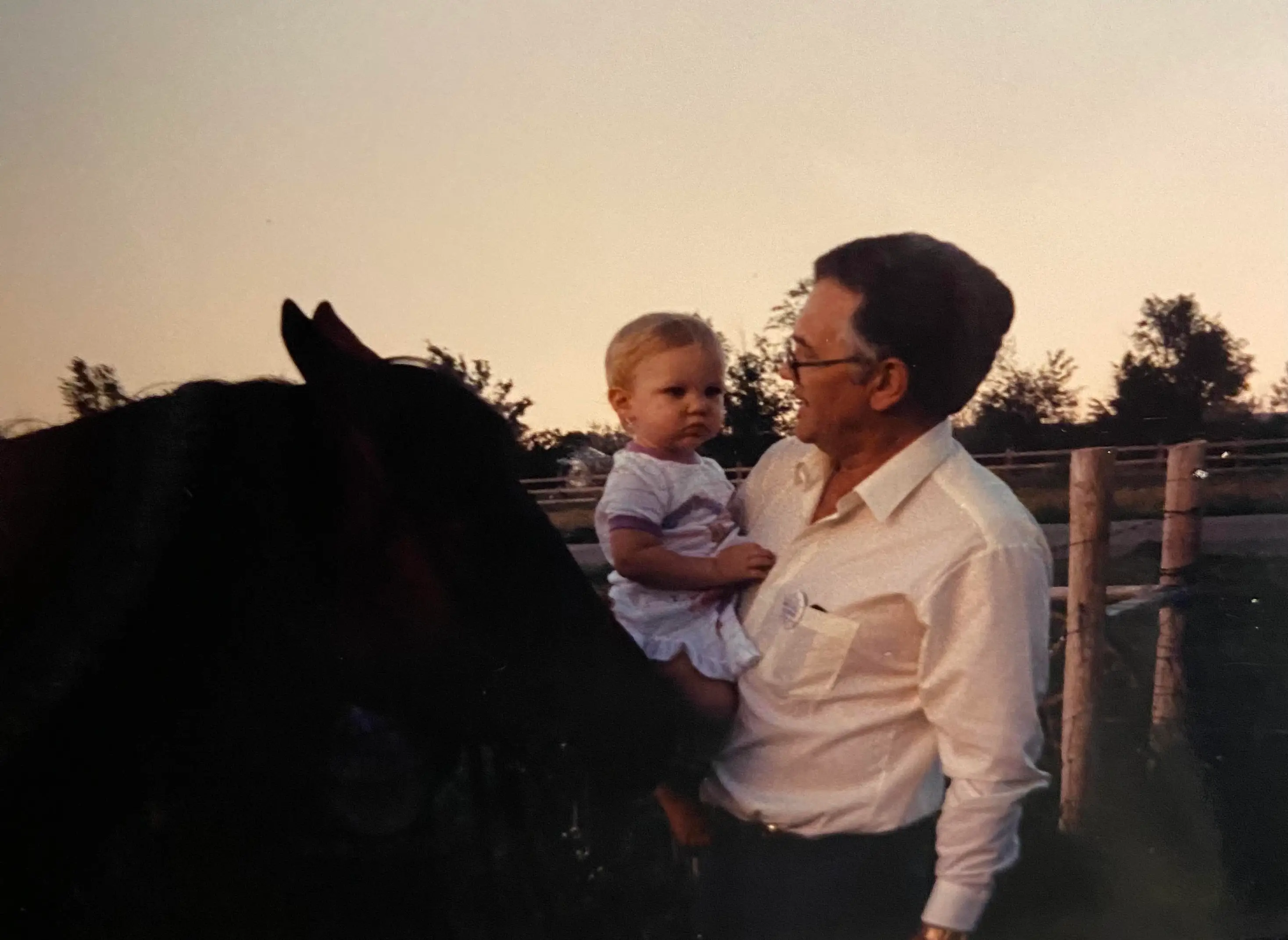 GRandfather holding baby next to a horse