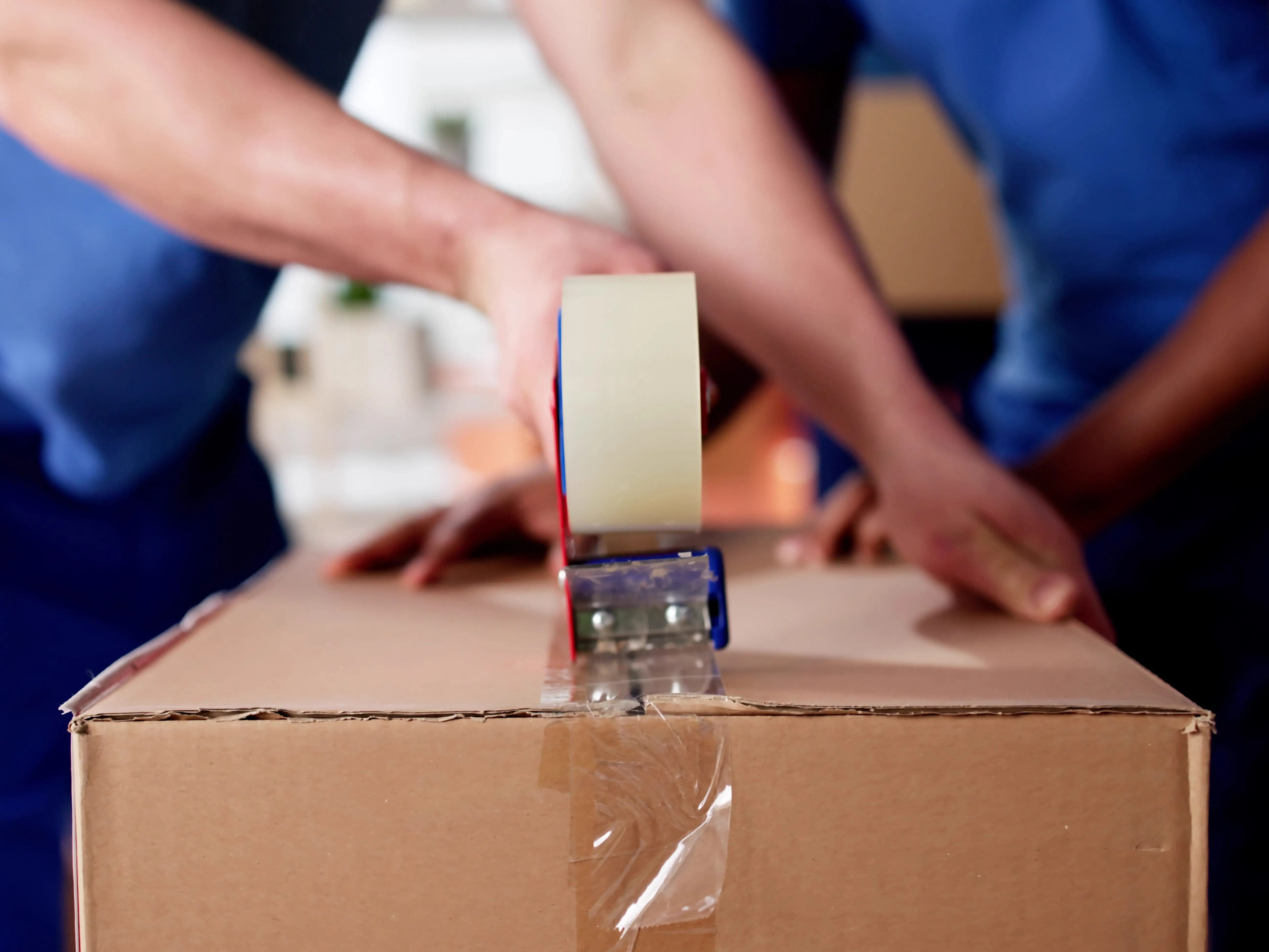 Movers tape up a box.