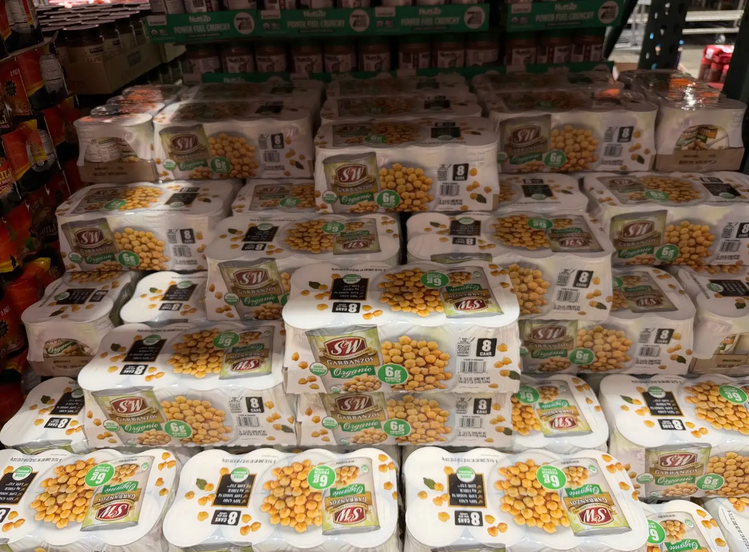 Stacks of S&W Organic garbanzo bean multipacks are displayed on store shelves in a retail aisle.