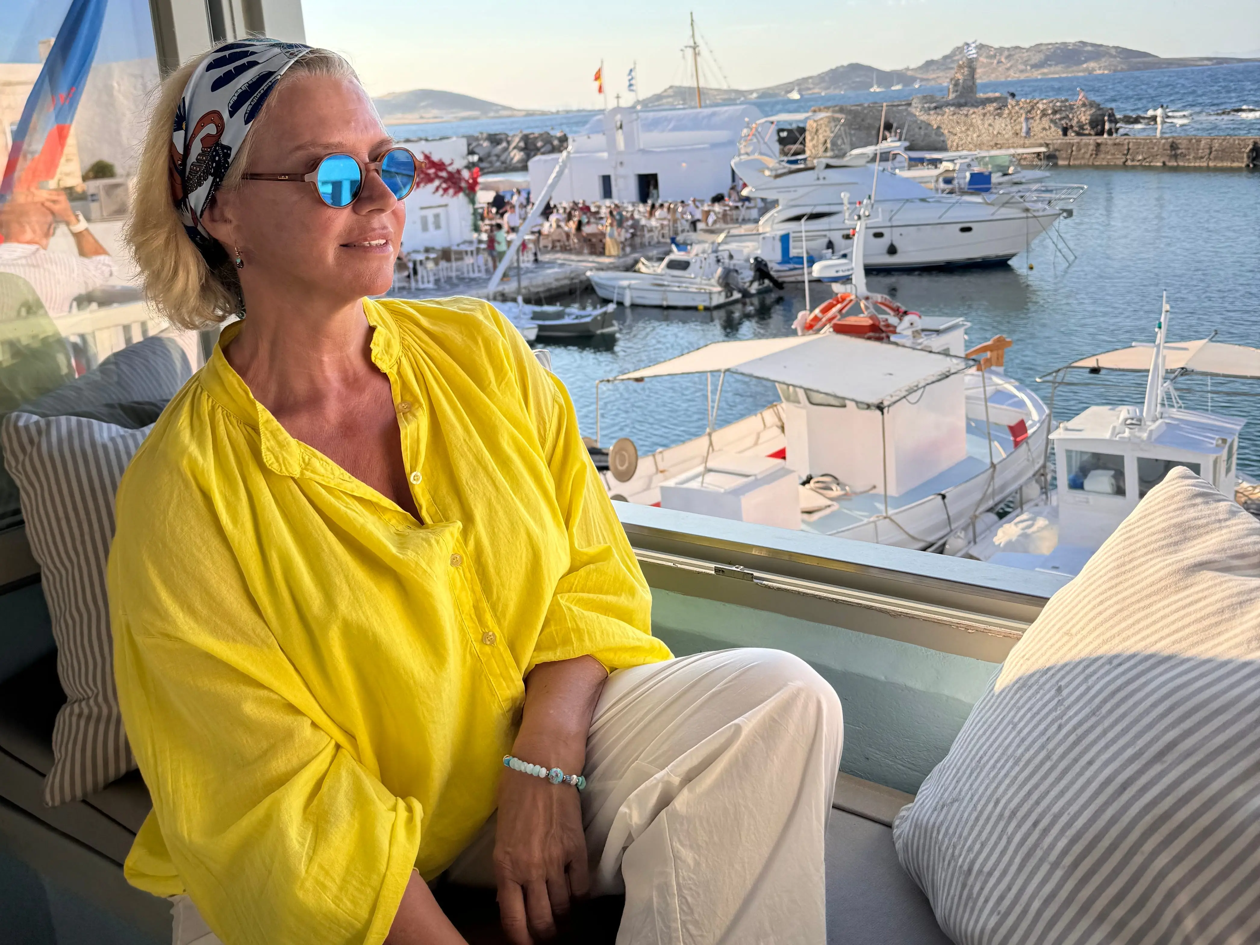 A woman in a yellow top looking out onto a harbor.