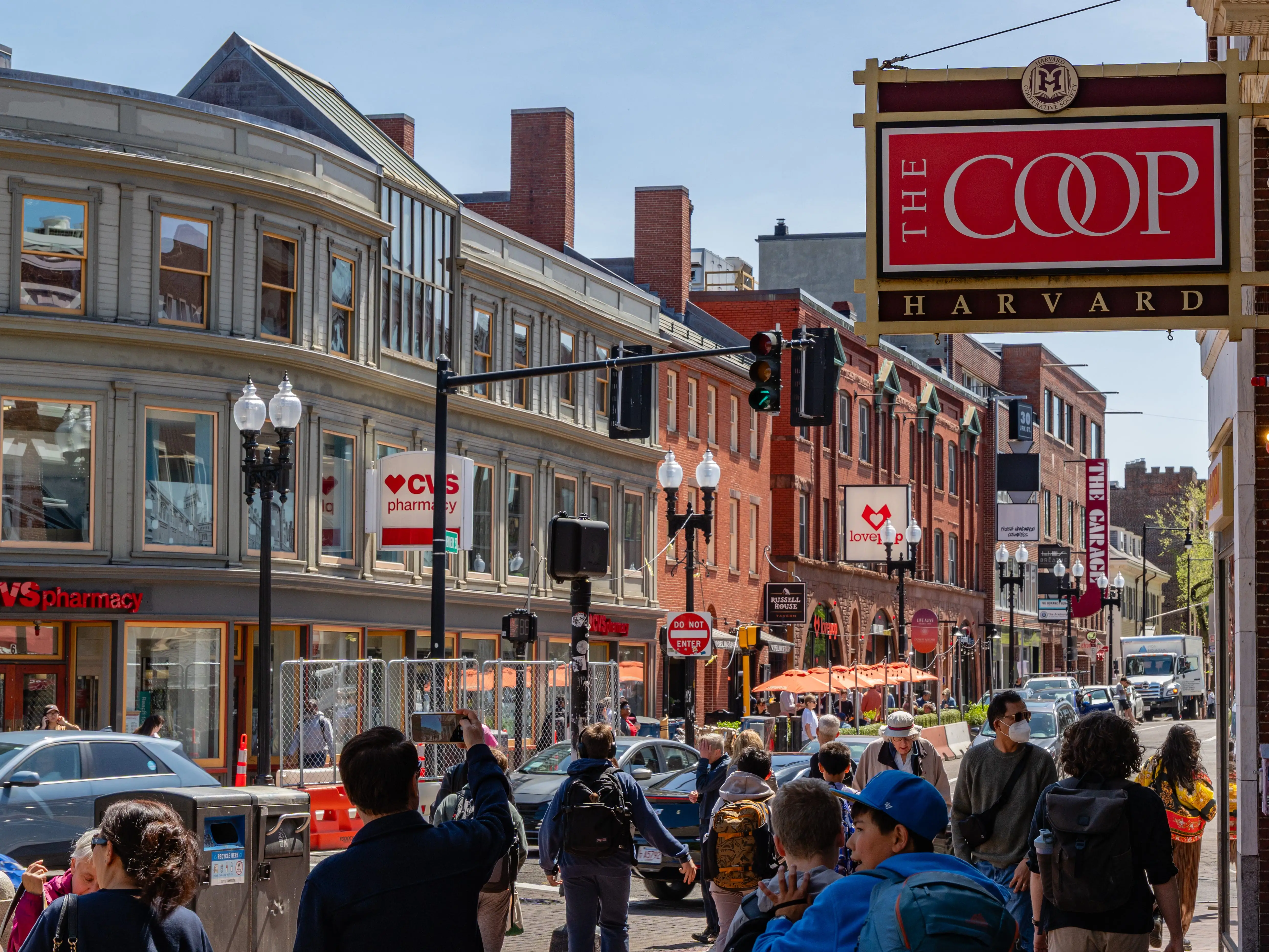 Cambridge, MA, US-May 1, 2025: Street scence in Harvard Square district with people walking by the Harvard Coop, Harvard University's bookstore.