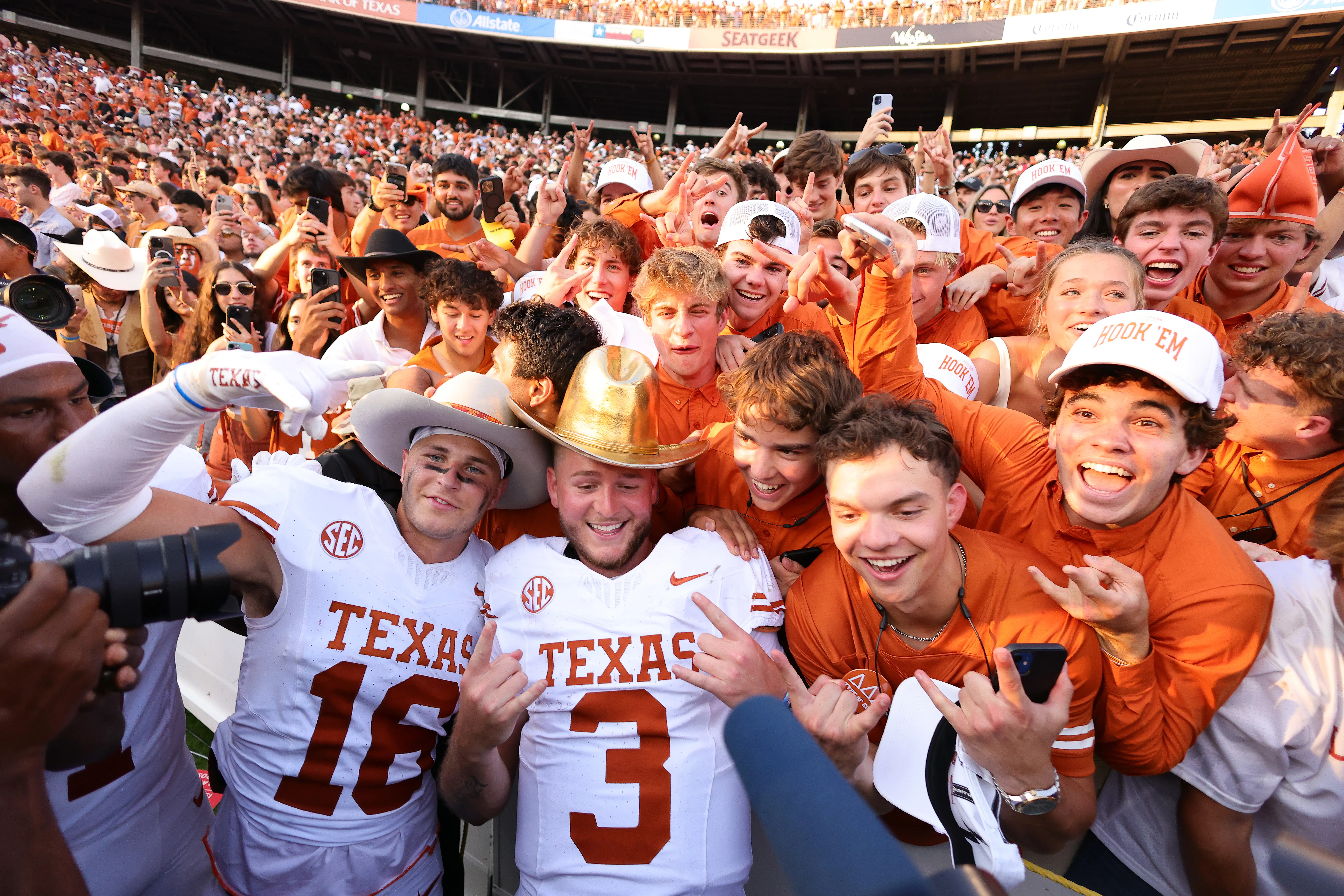 Quinn Ewers #3 of the Texas Longhorns poses with fans and teammates while wearing the Golden Hat Trophy after defeating the Oklahoma Sooners 34-3 at Cotton Bowl Stadium on October 12, 2024 in Dallas, Texas.