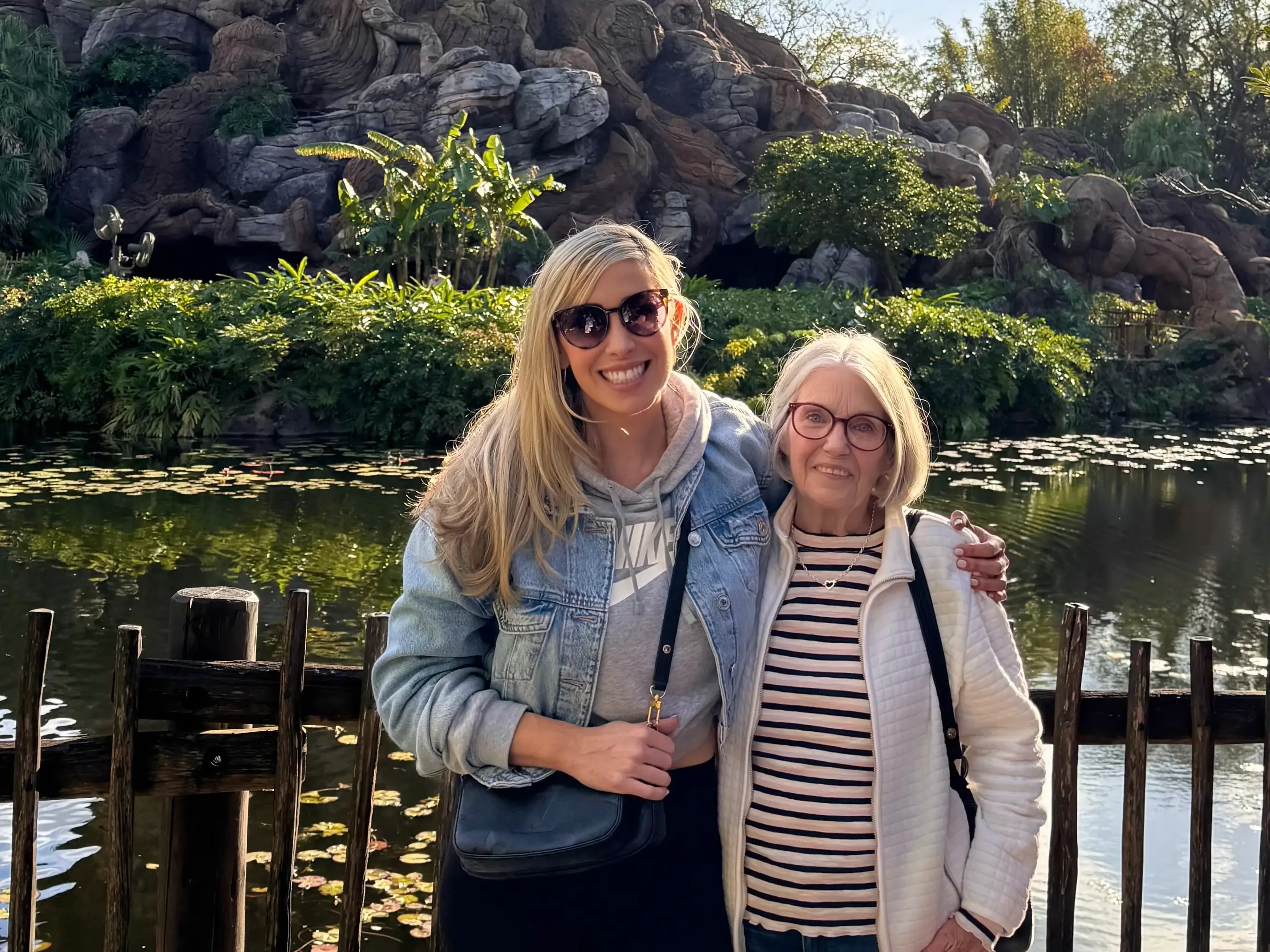 Two woman smiling in front of greenery