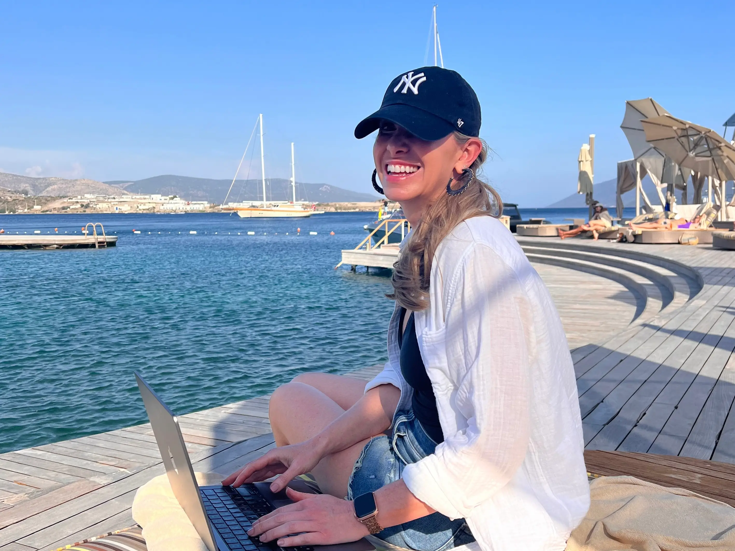 woman in hat smiling by water