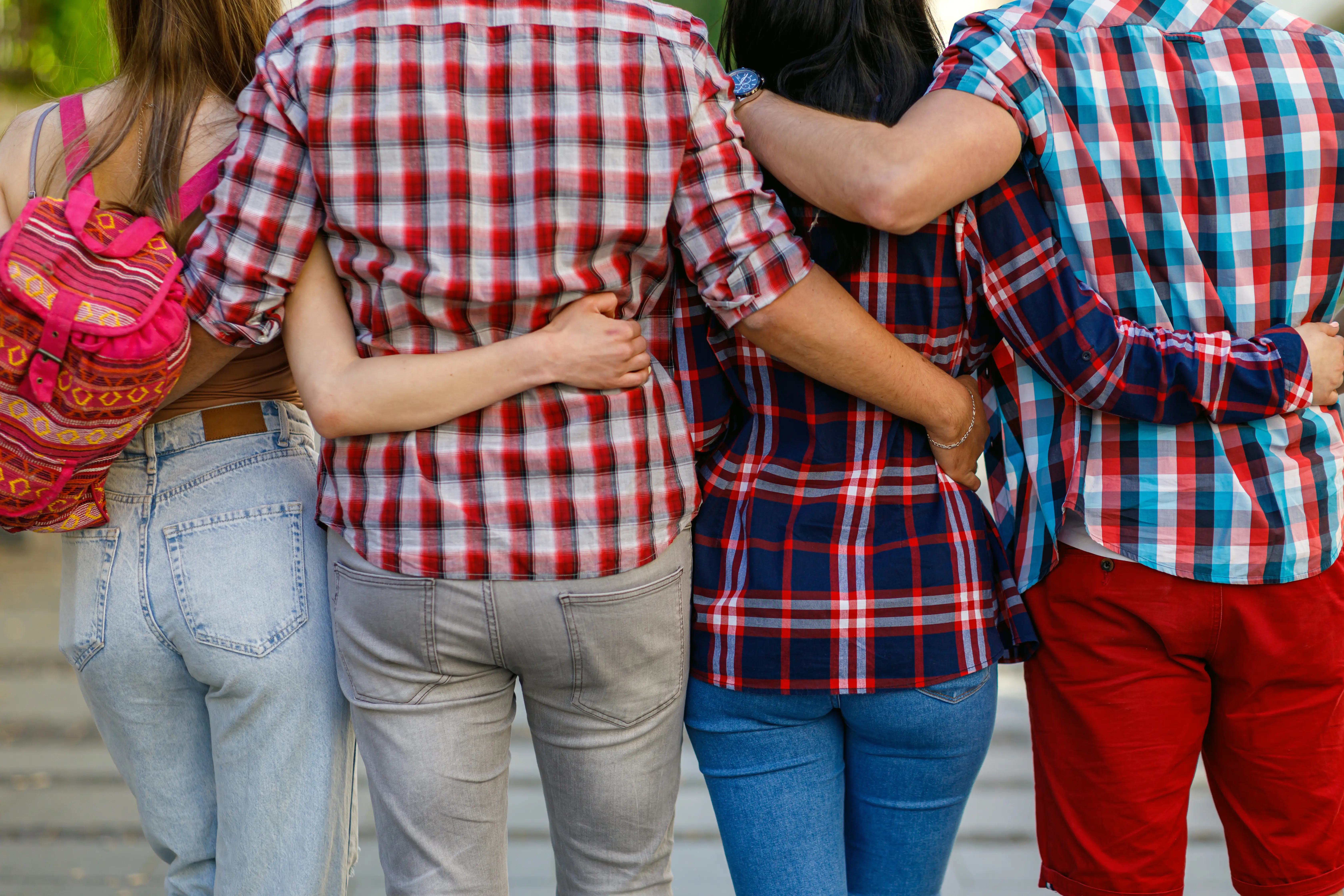 A family is shown from behind with their arms wrapped around each other.