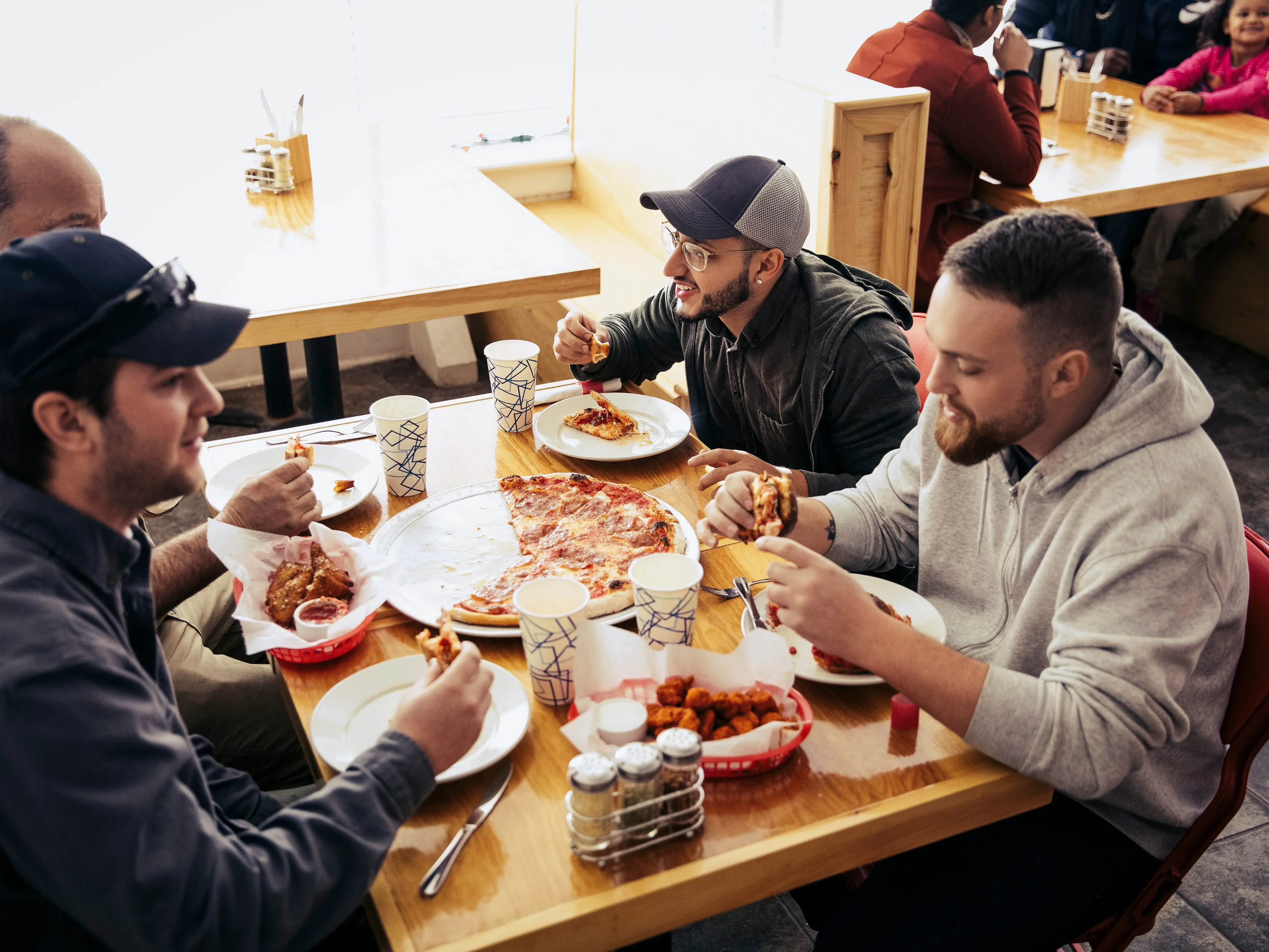 People eating pizza and other items at a food establishment