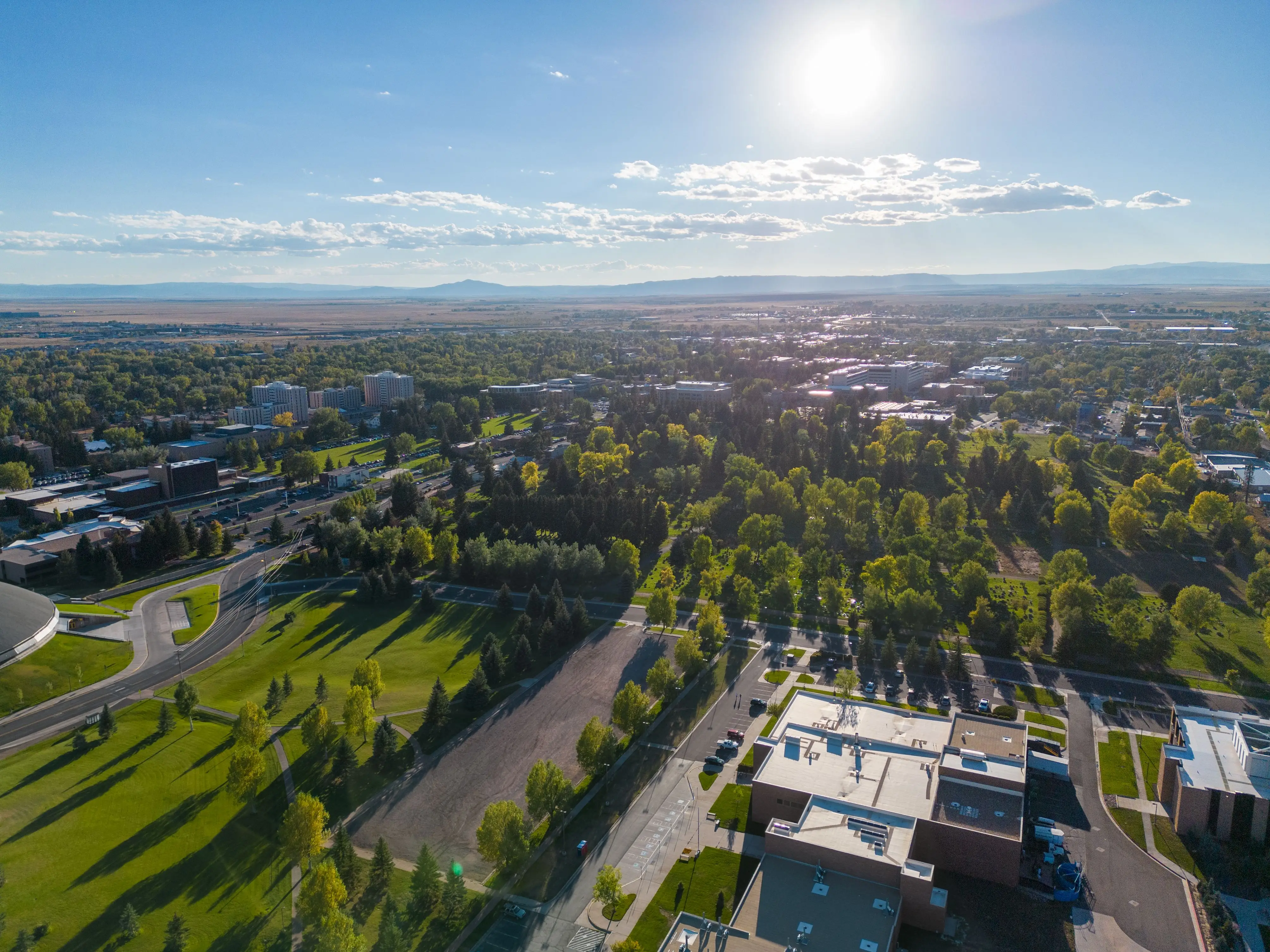 A drone shot of Laramie, Wyoming neighborhood's cityscape with greenery, sunlight and cloudy sky