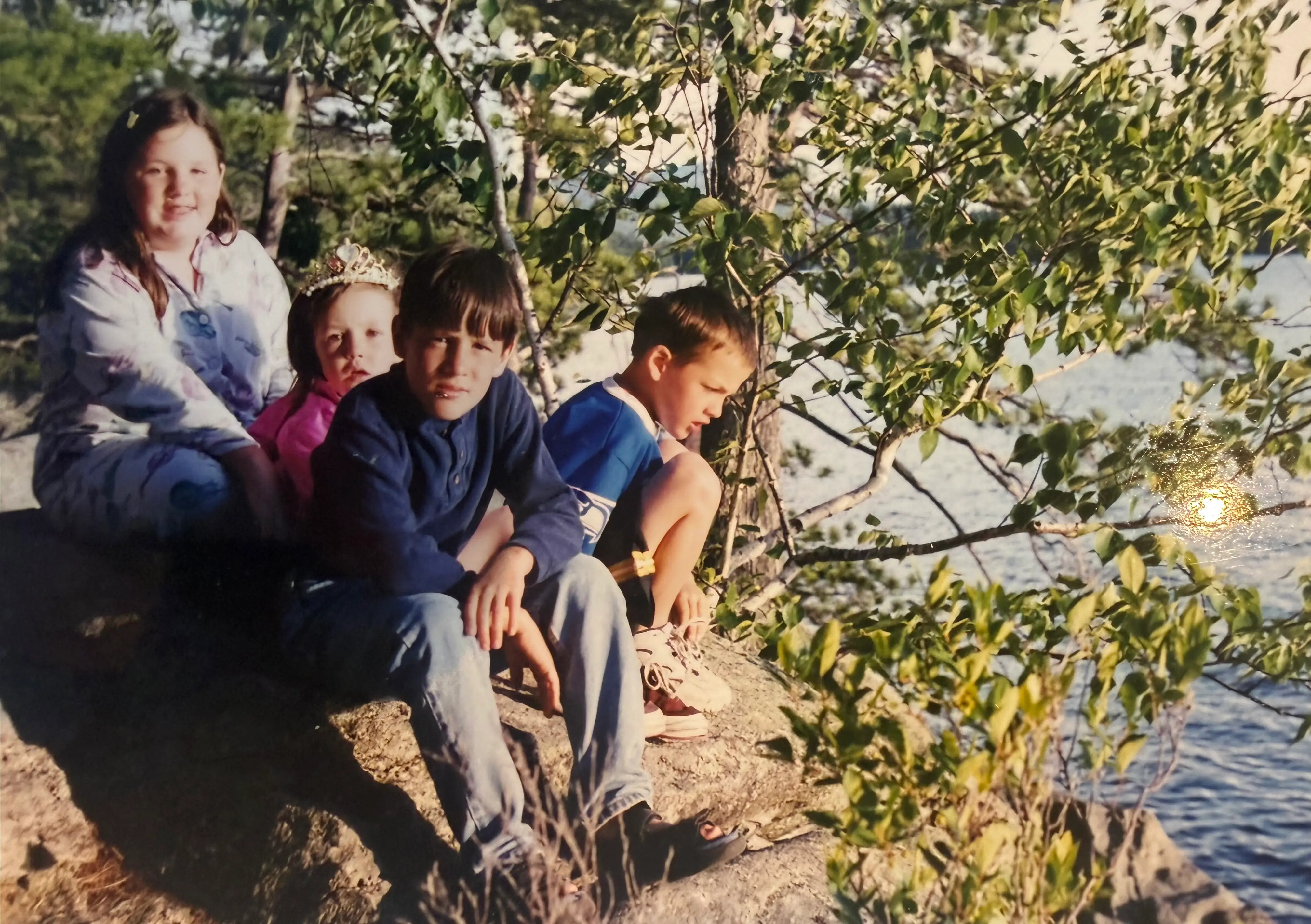 The author (left) and her siblings sit next to a lake in 1999.