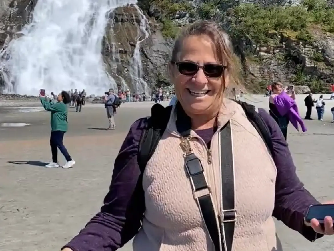 Woman smiling in Alaska with falls behind her