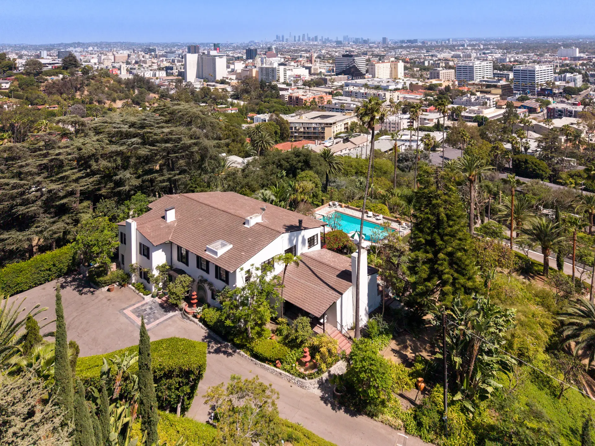 Aerial view of a hillside estate with pool overlooking a sprawling Los Angeles city skyline.