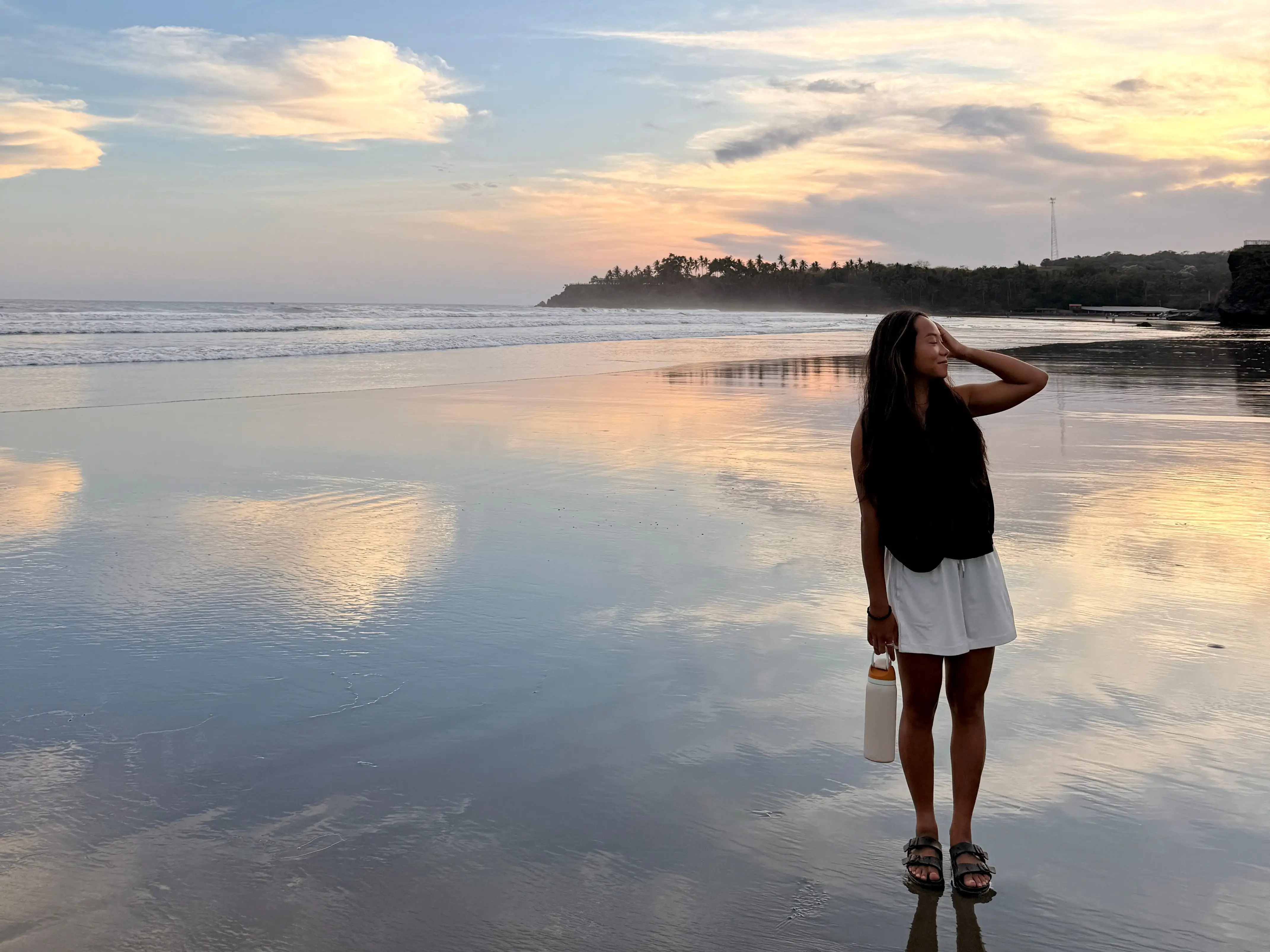 Alice Kim standing on the shore with the sunset forming in the background