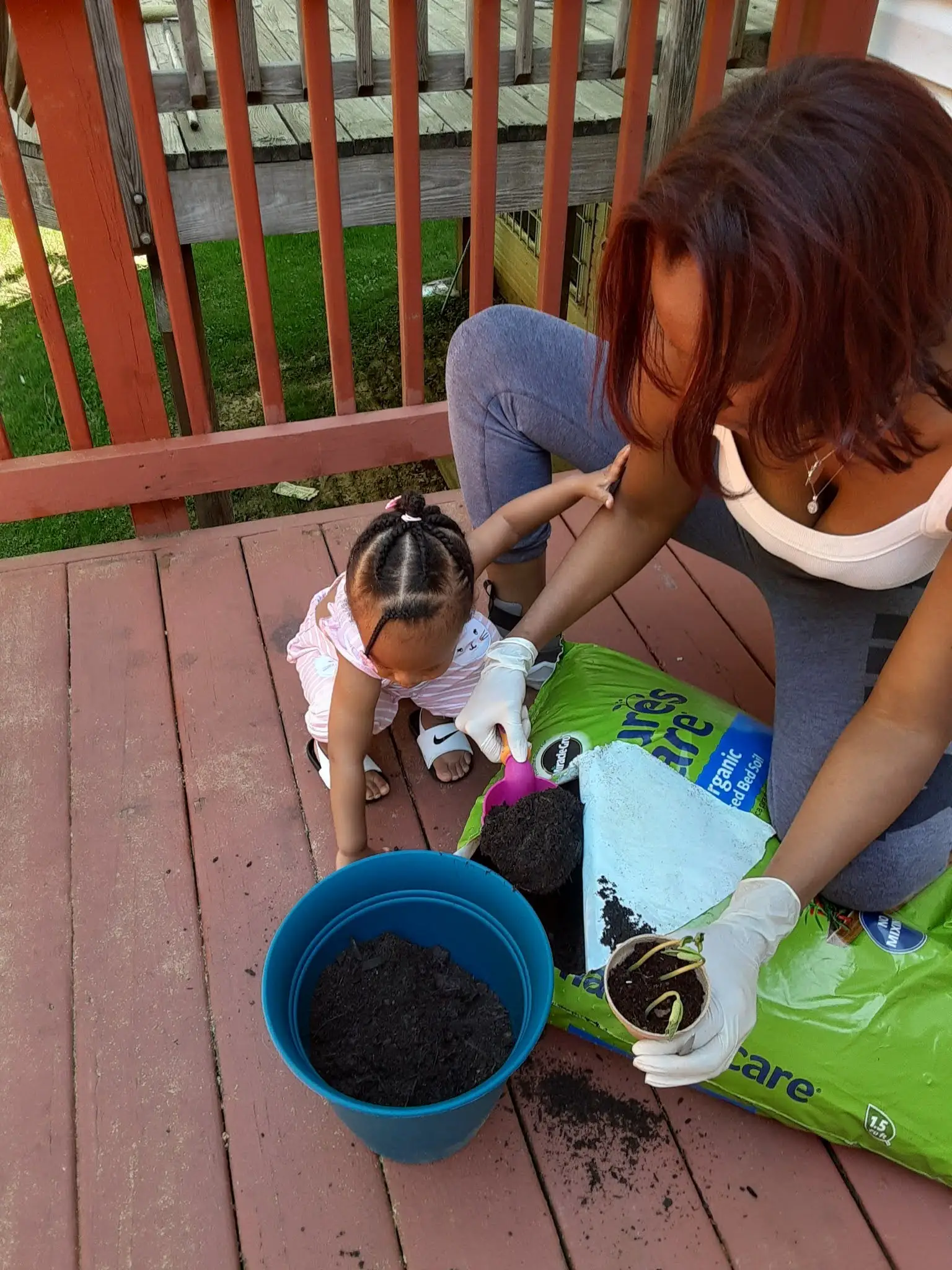 Woman with child and potting soil in yard