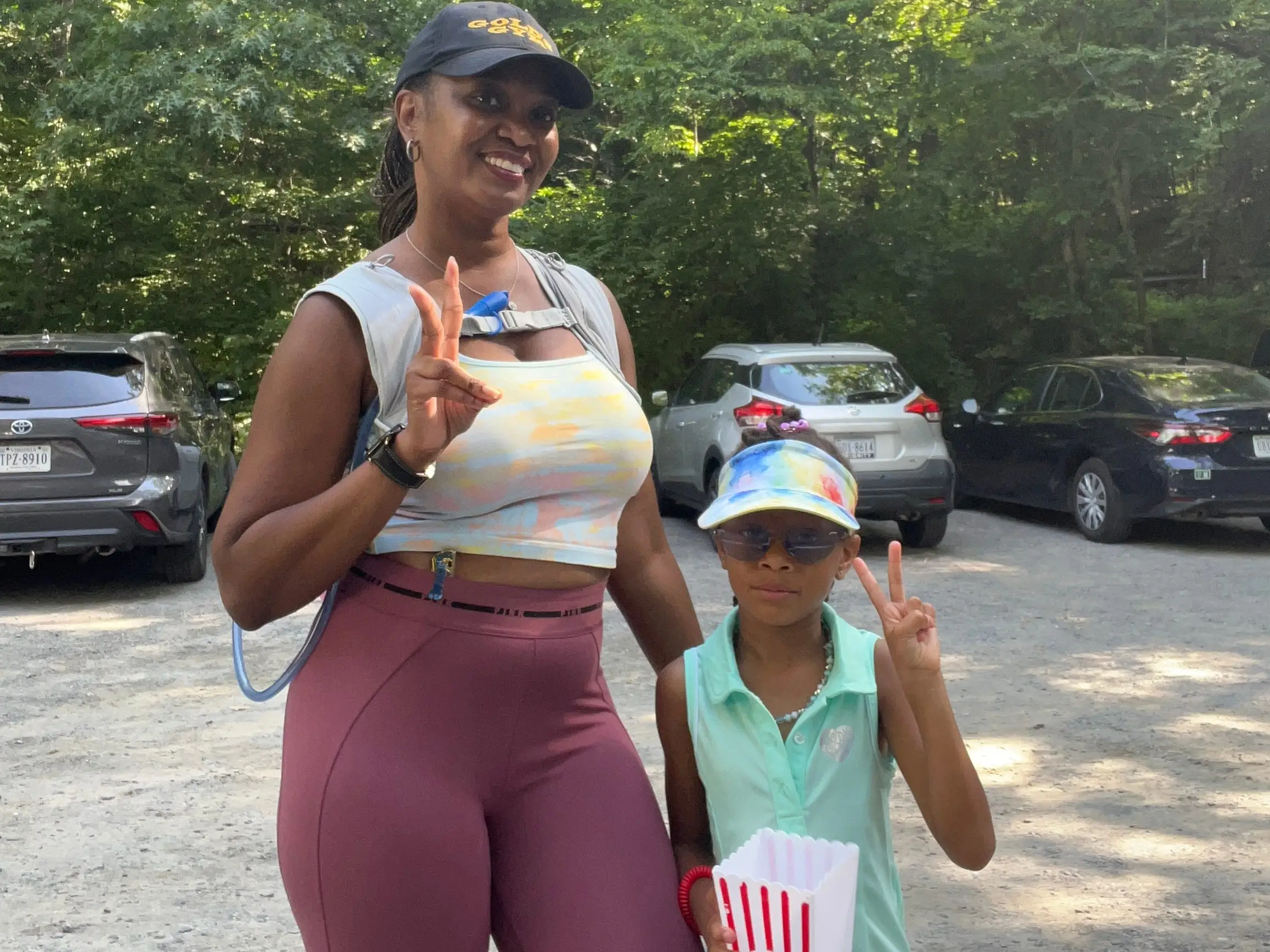 Woman and child with hats on in parking lot, smiling