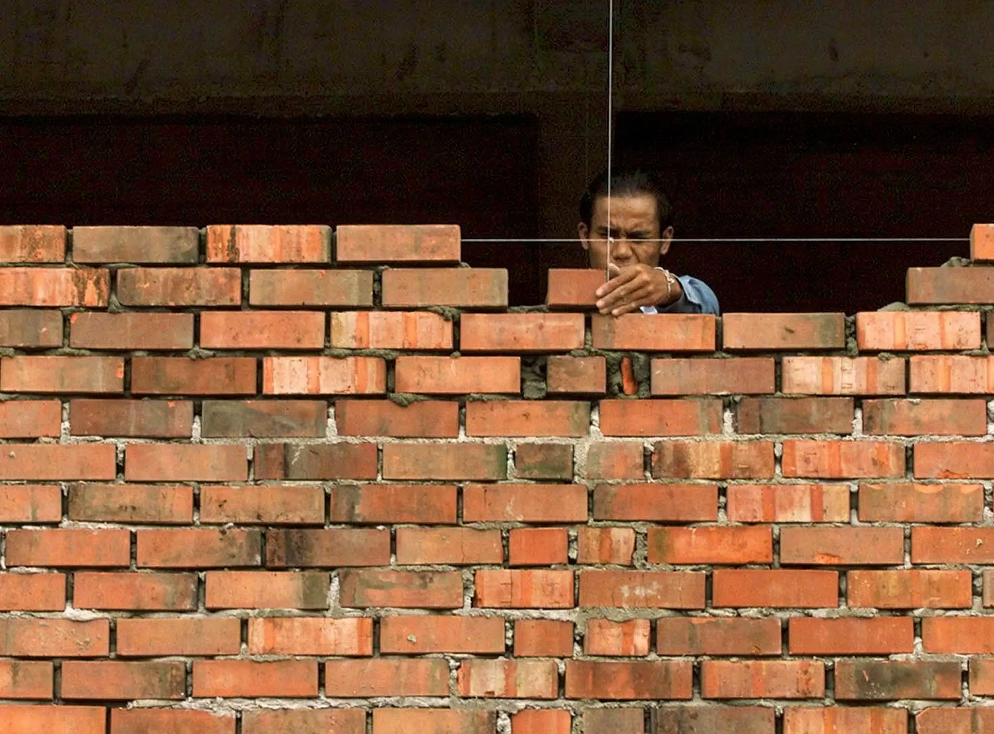 A bricklayer builds a wall at a construction site in Kuala Lumpur