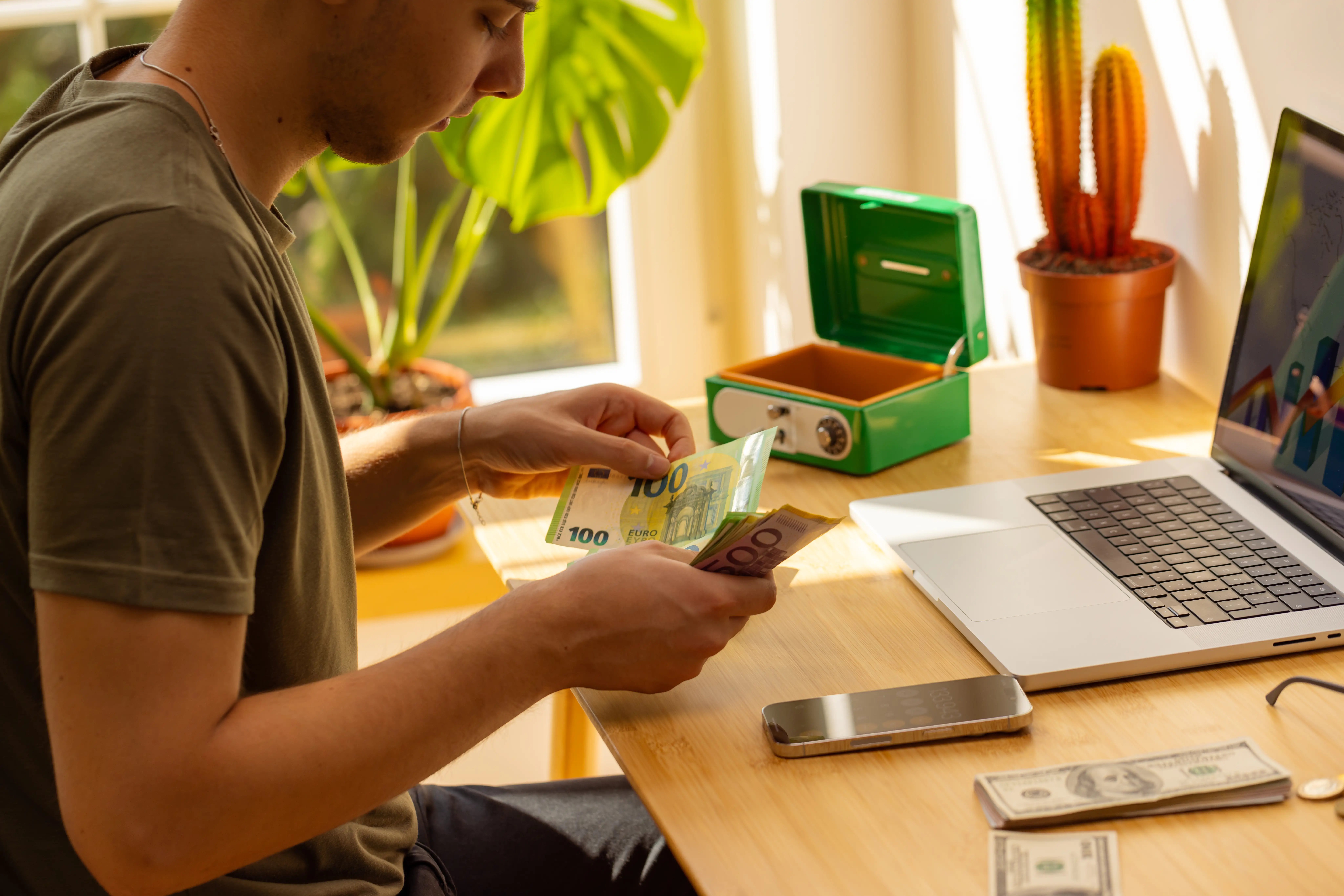A young boy sits at a computer counting cash.