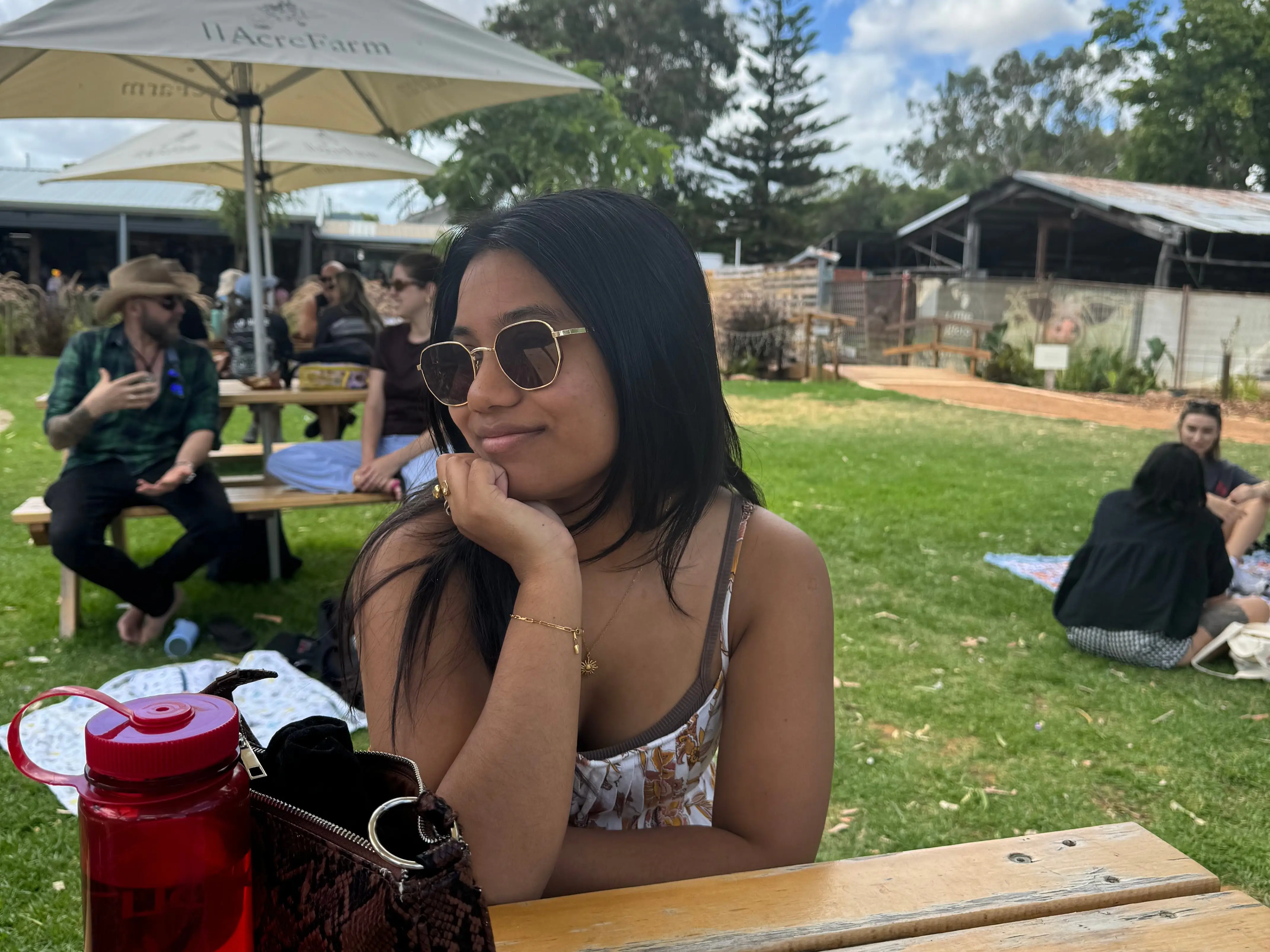 The writer wearing sunglasses and sitting outside at a picnic table.