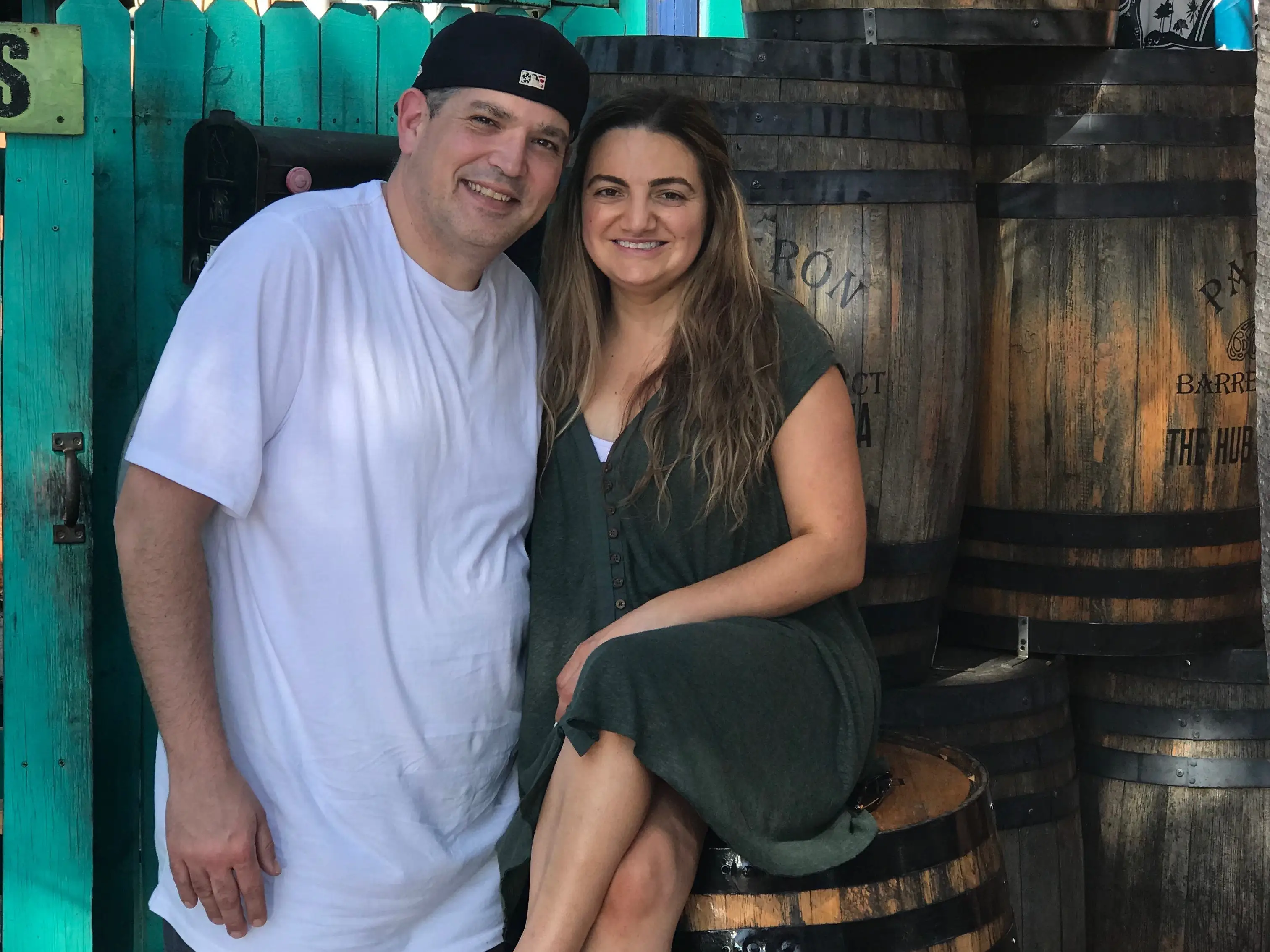 Man and woman smiling in front of barrels