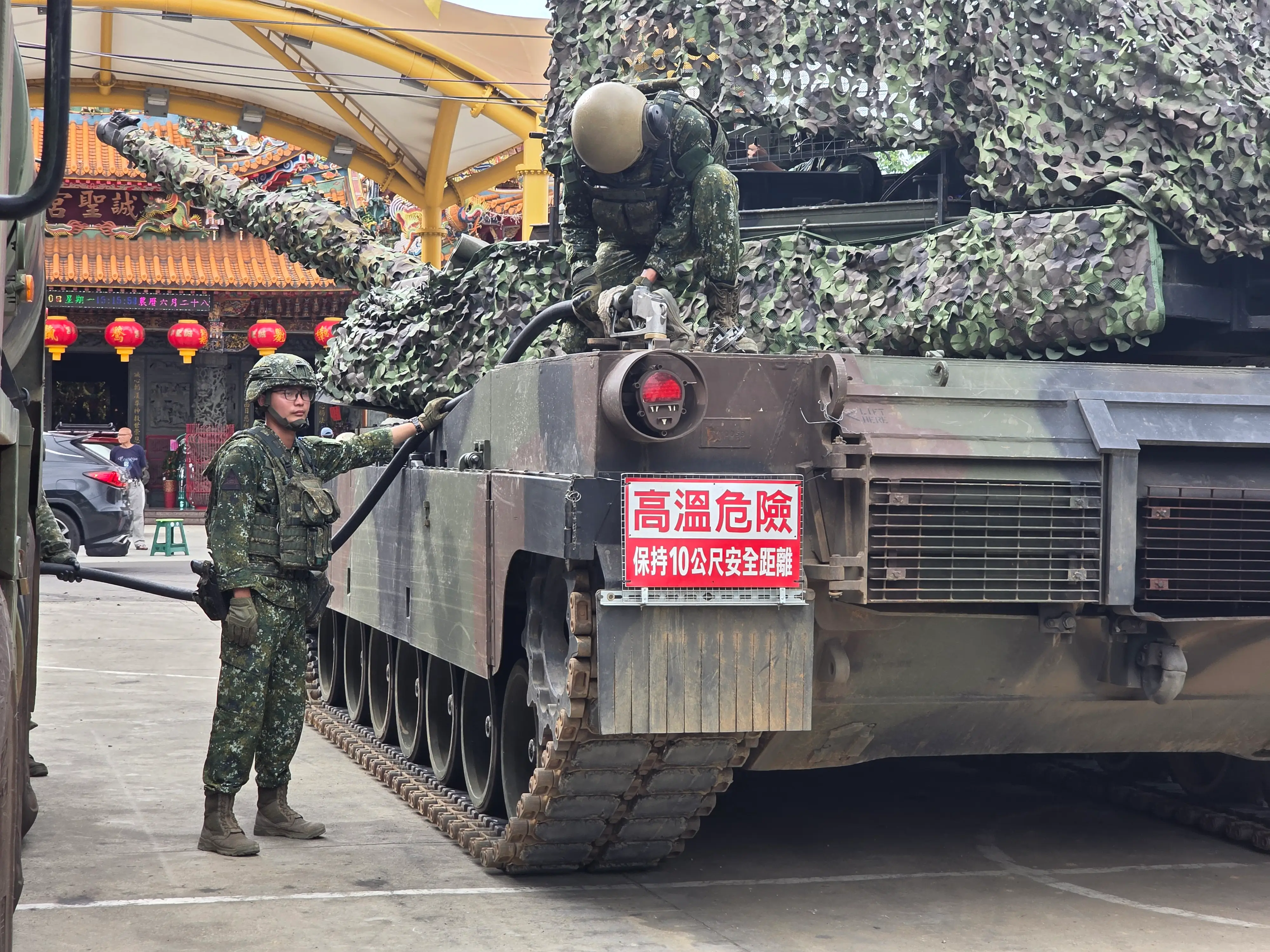 Taiwanese troops refuel an M1A2T across from a Chinese temple.
