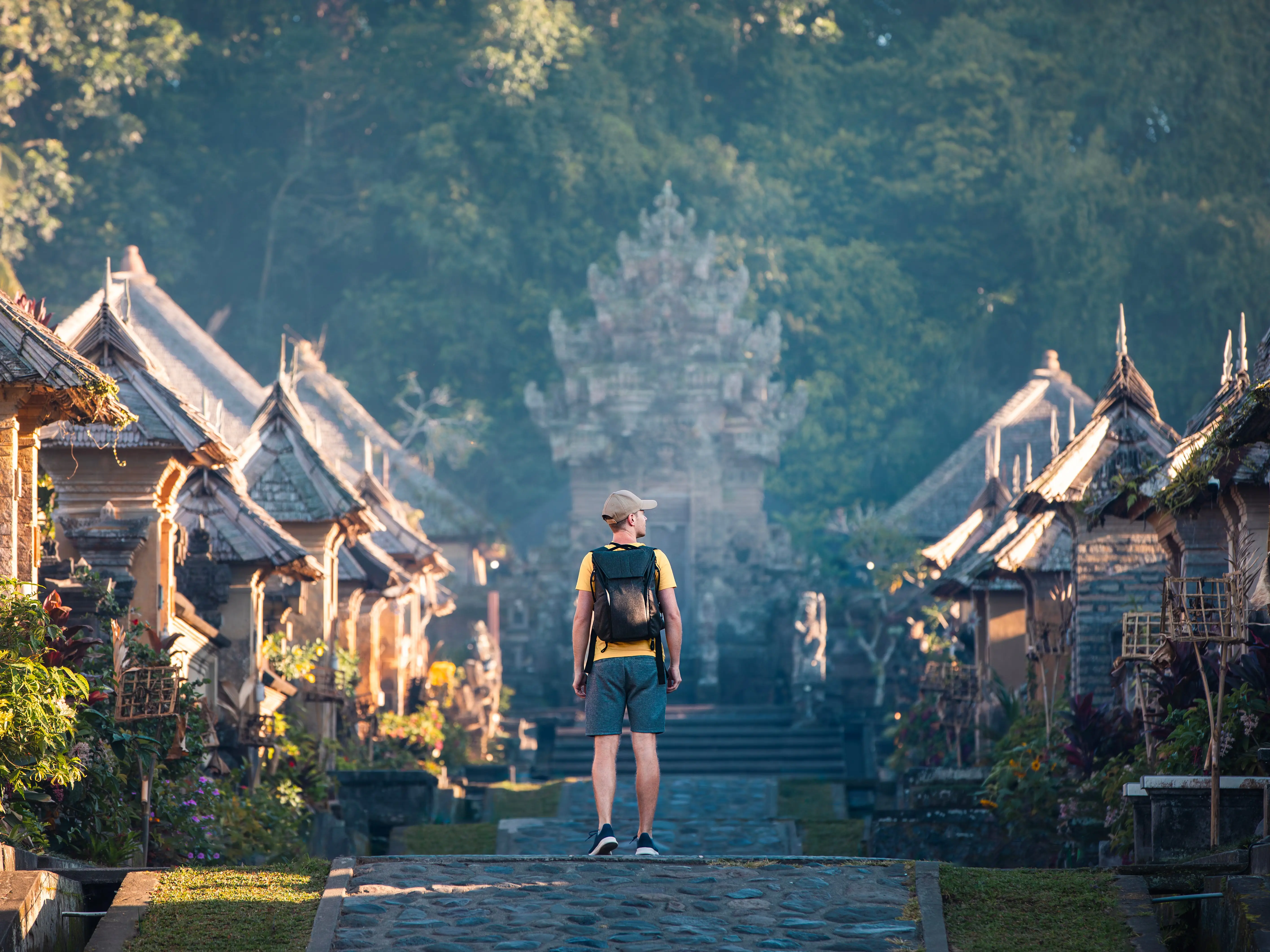 A tourist with a backpack exploring Penglipuran historical village on the island of Bali in Indonesia.